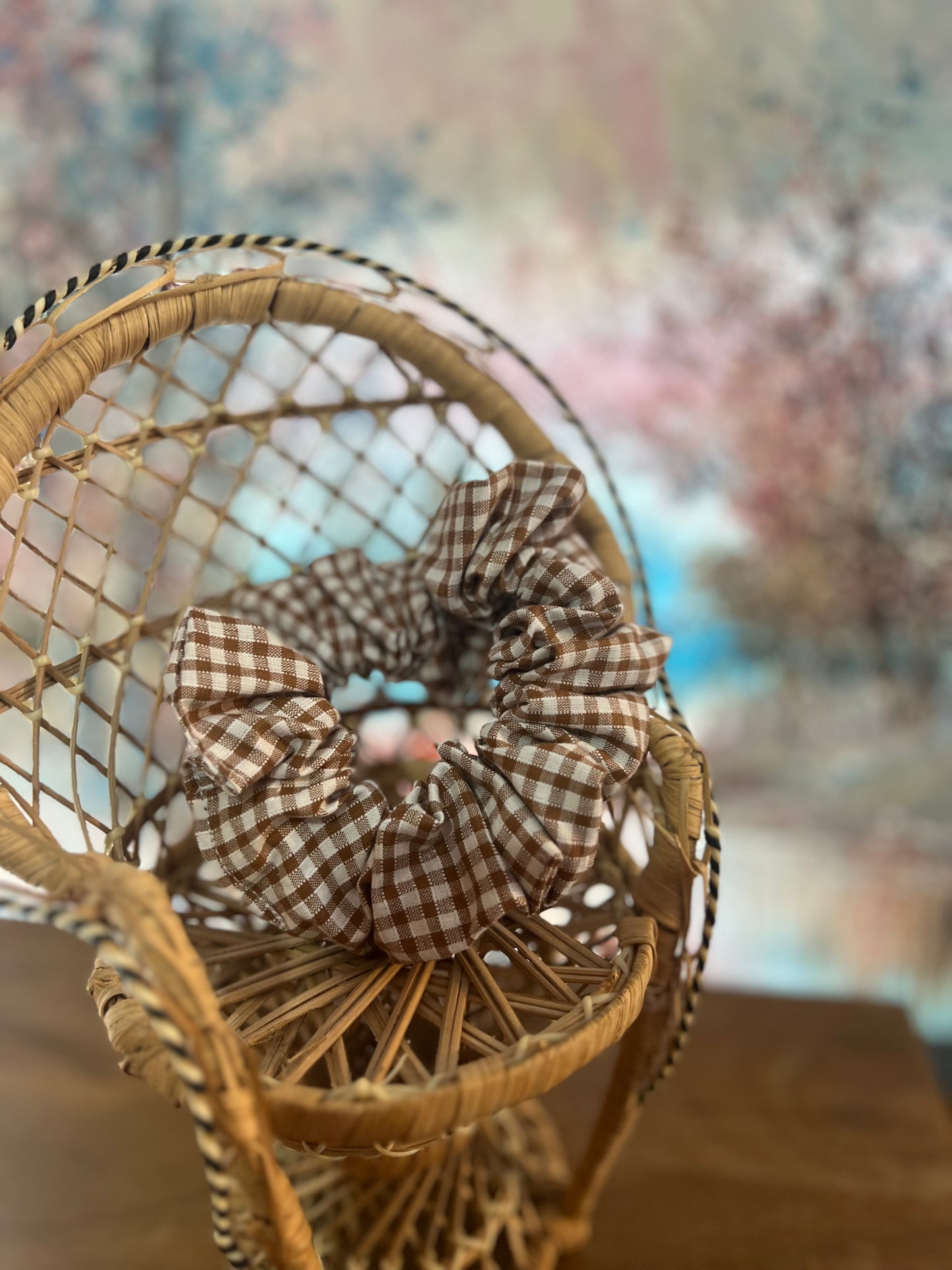 Wicker basket with a checkered scrunchie on a blurred floral background