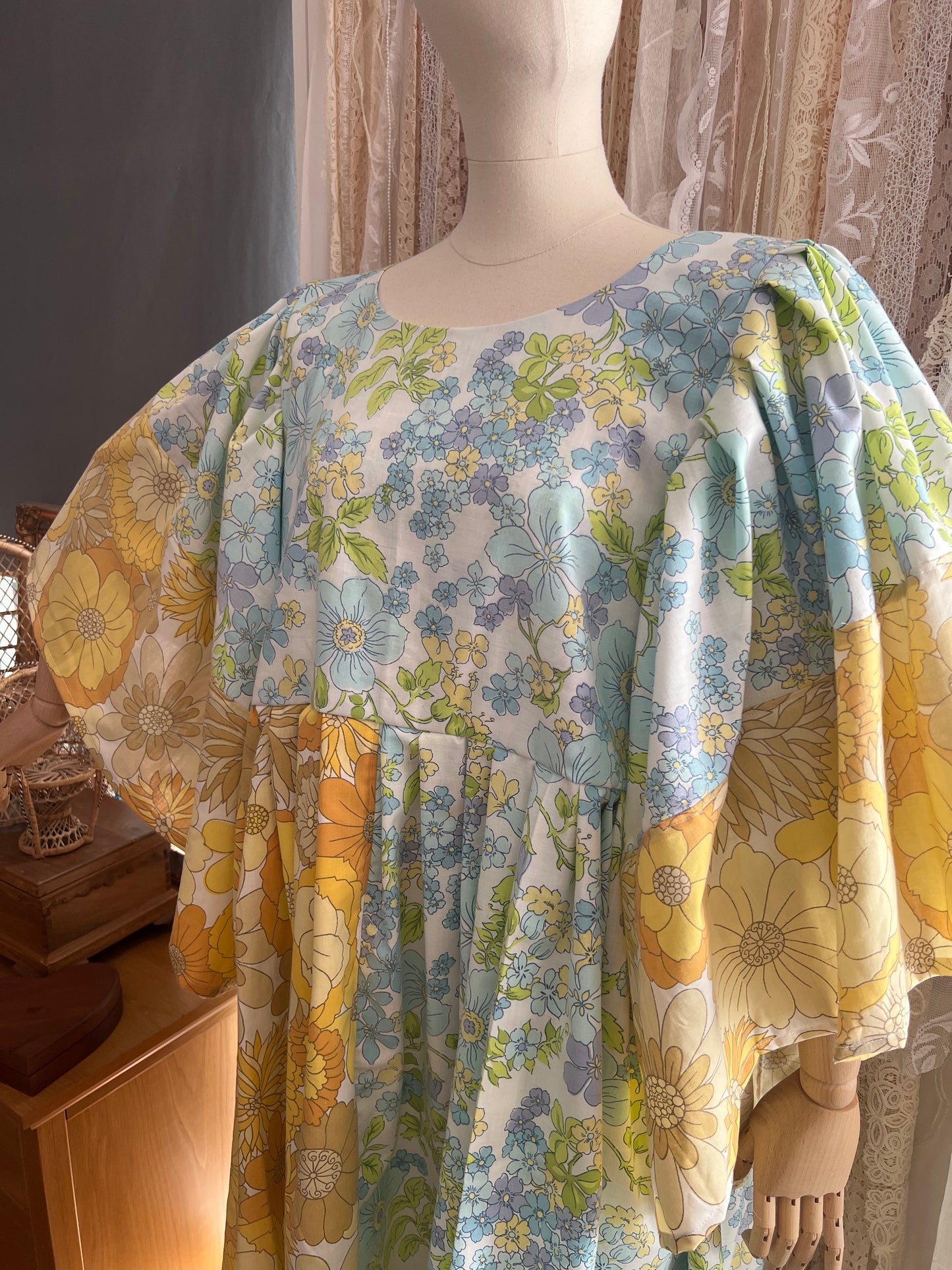 Mannequin wearing a floral dress with yellow and blue flowers in a room.