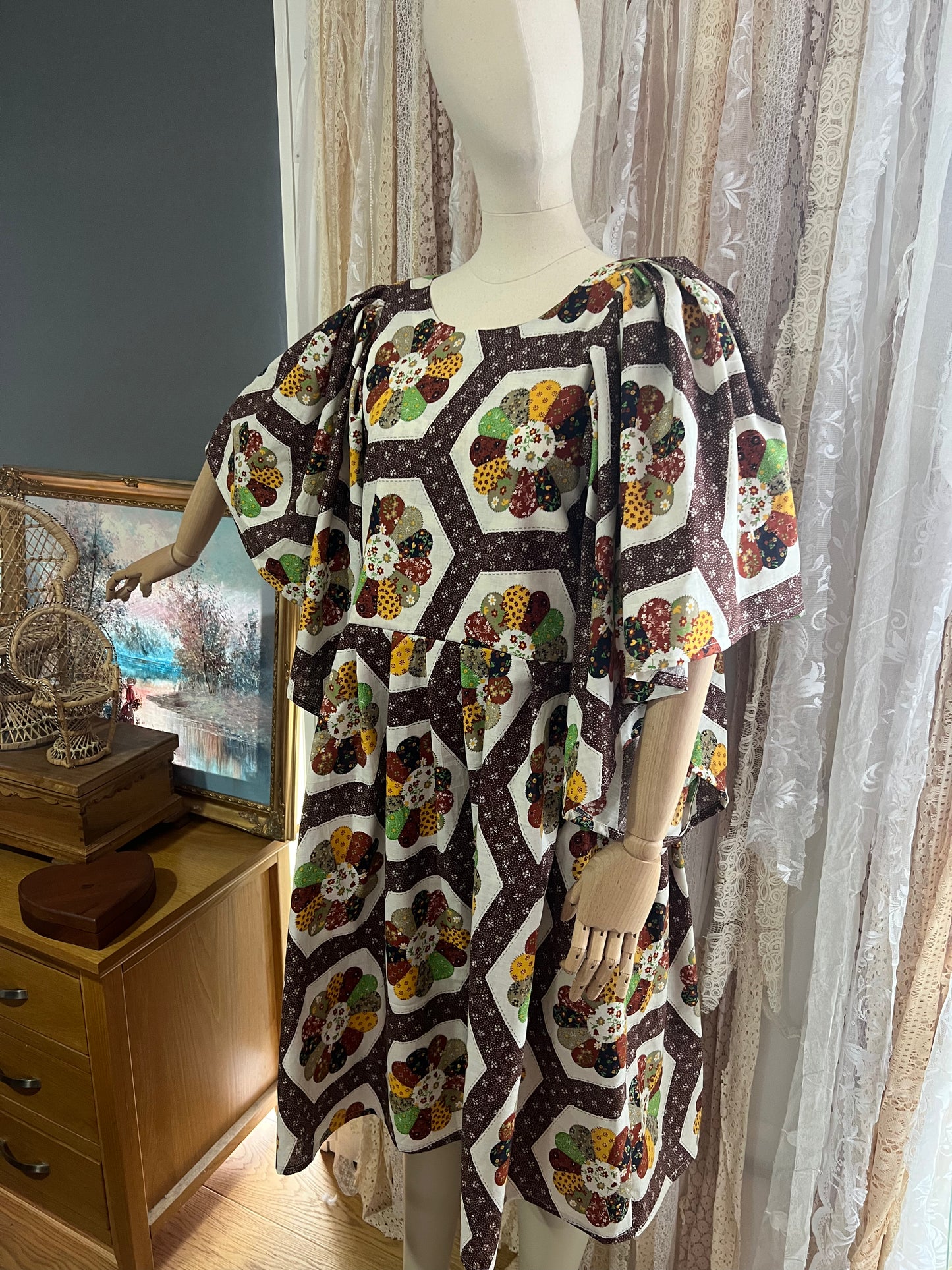 Mannequin wearing a floral patterned dress in a room with curtains and a painting.