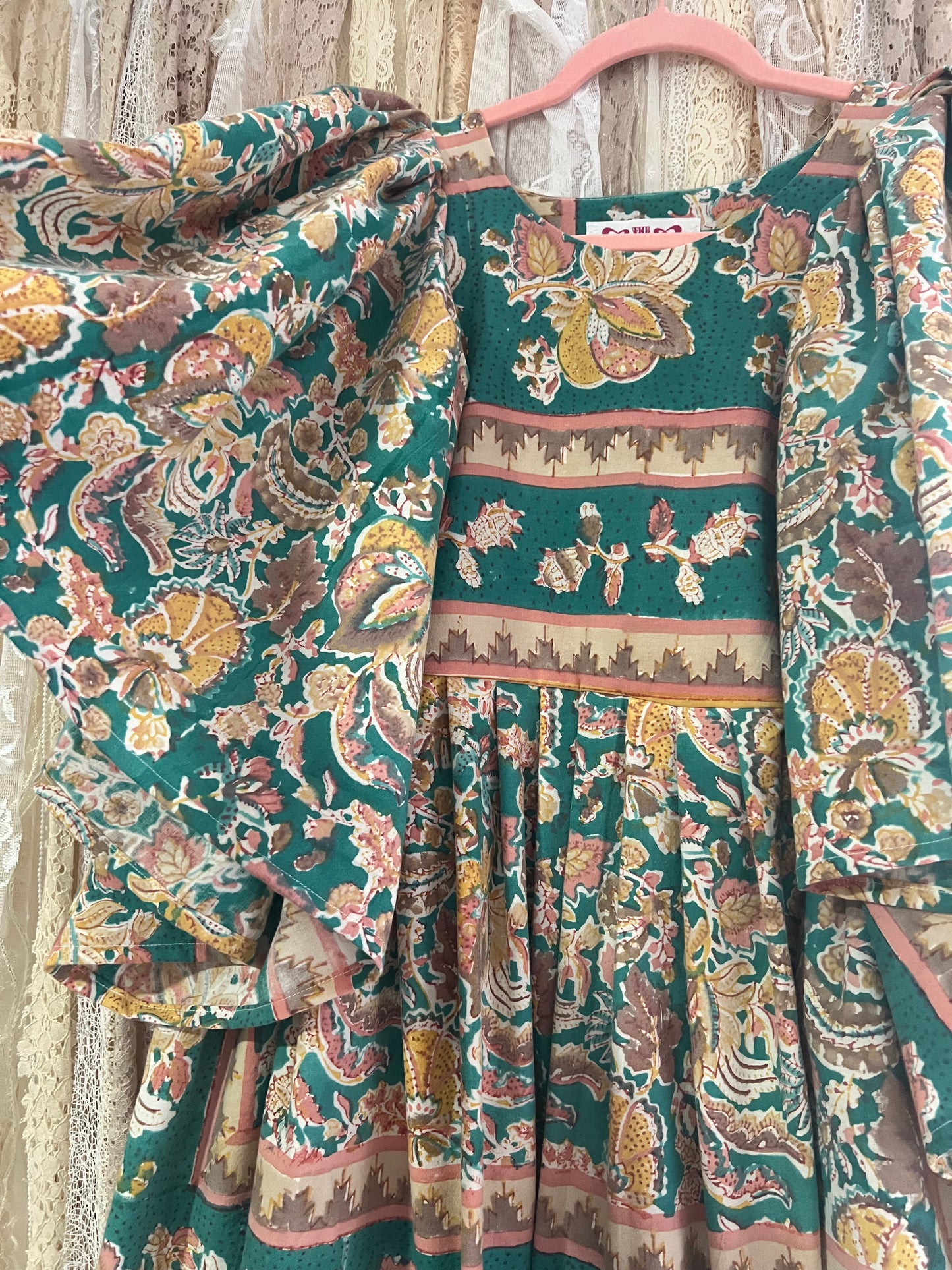 Floral patterned dress on a hanger against a neutral background