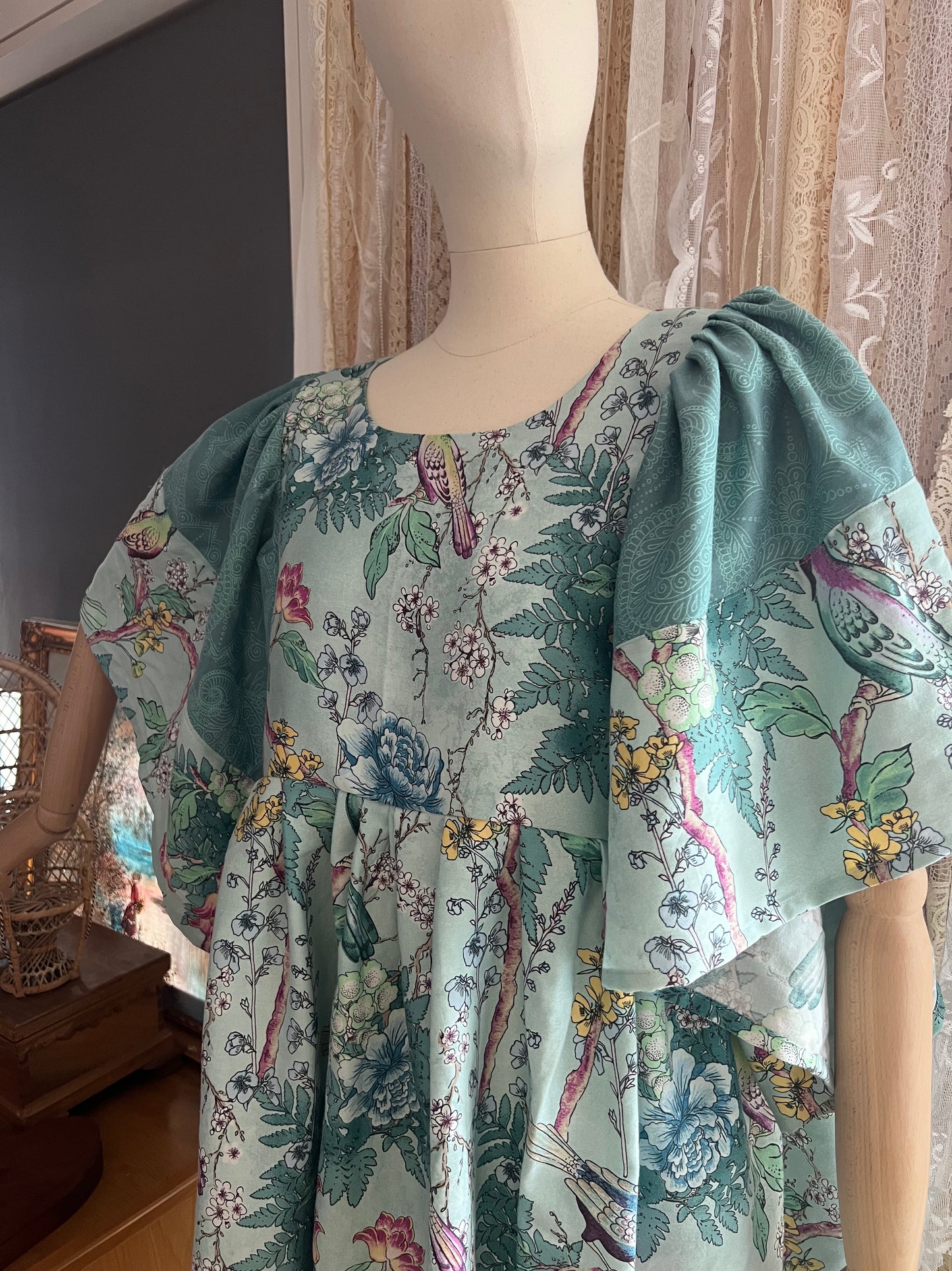 Floral dress with green accents on a mannequin against a neutral background