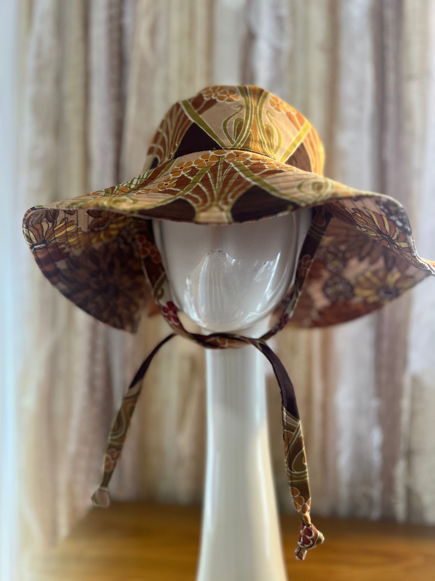 Floral patterned sun hat on a mannequin head against a neutral background