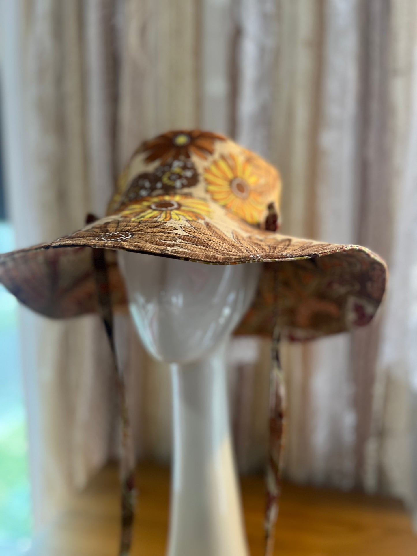 Floral patterned sun hat on a mannequin against a neutral background