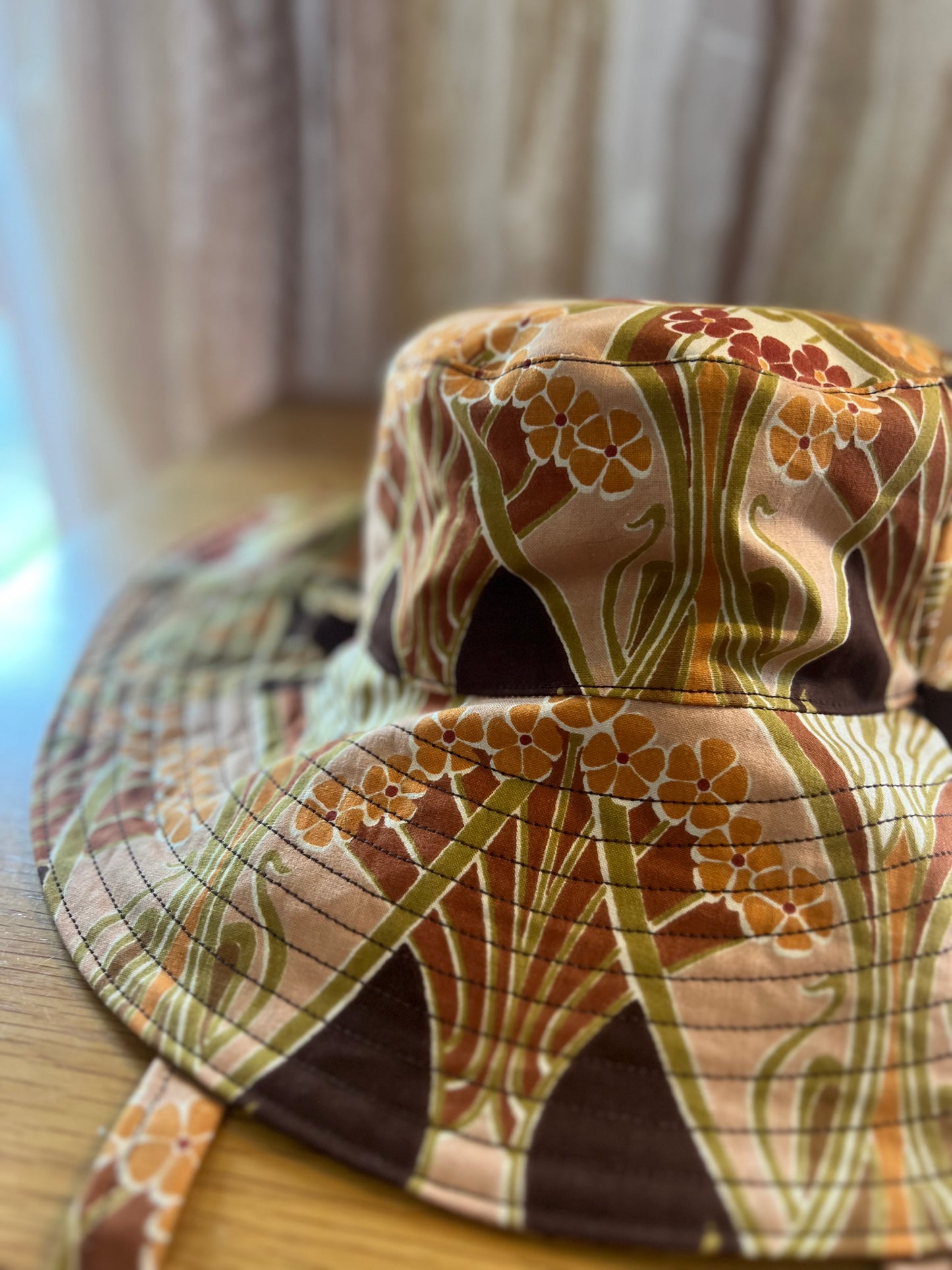 Floral patterned bucket hat on a wooden surface with a blurred background