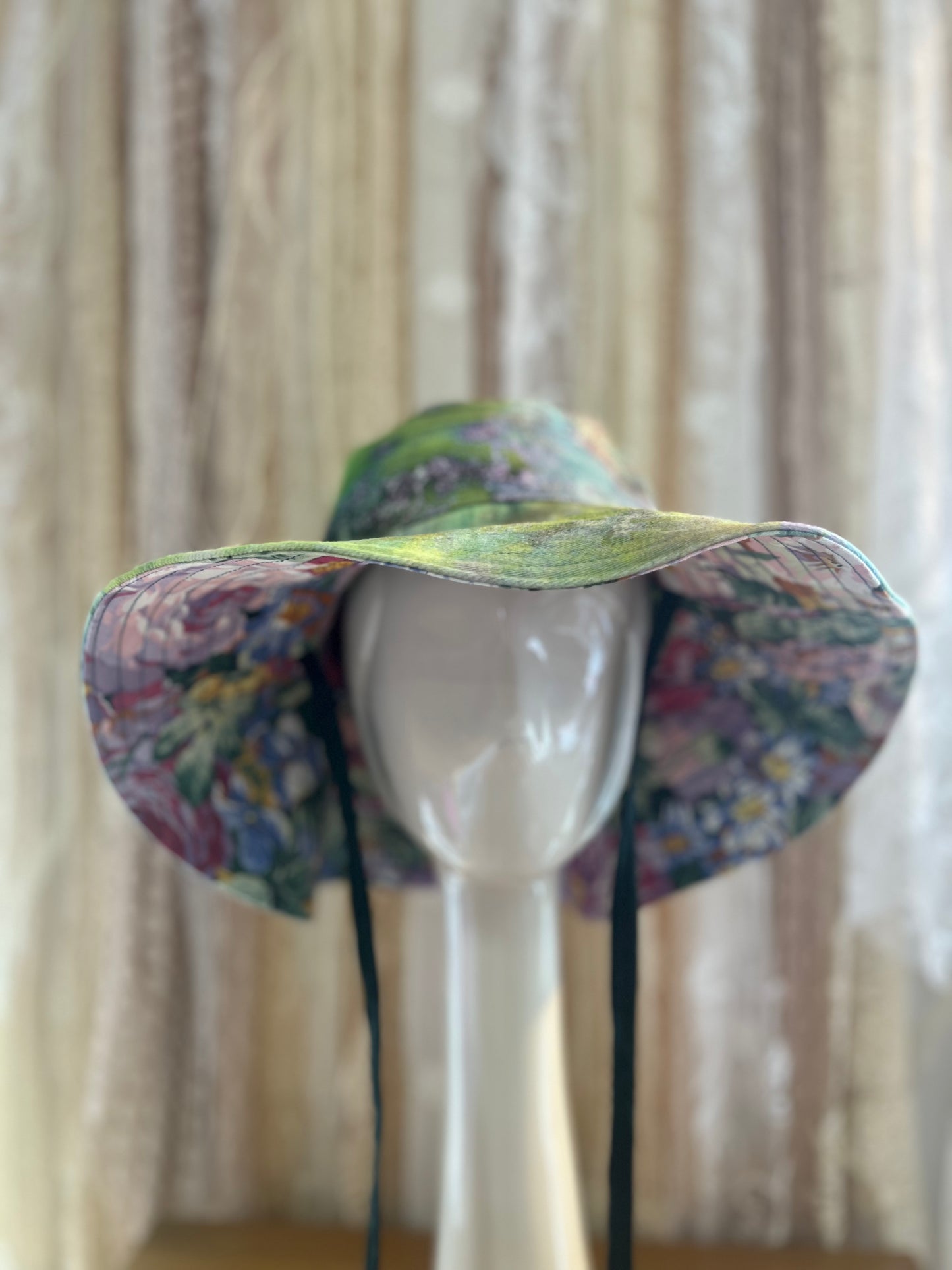Colorful floral-patterned sun hat on a mannequin head against a neutral background