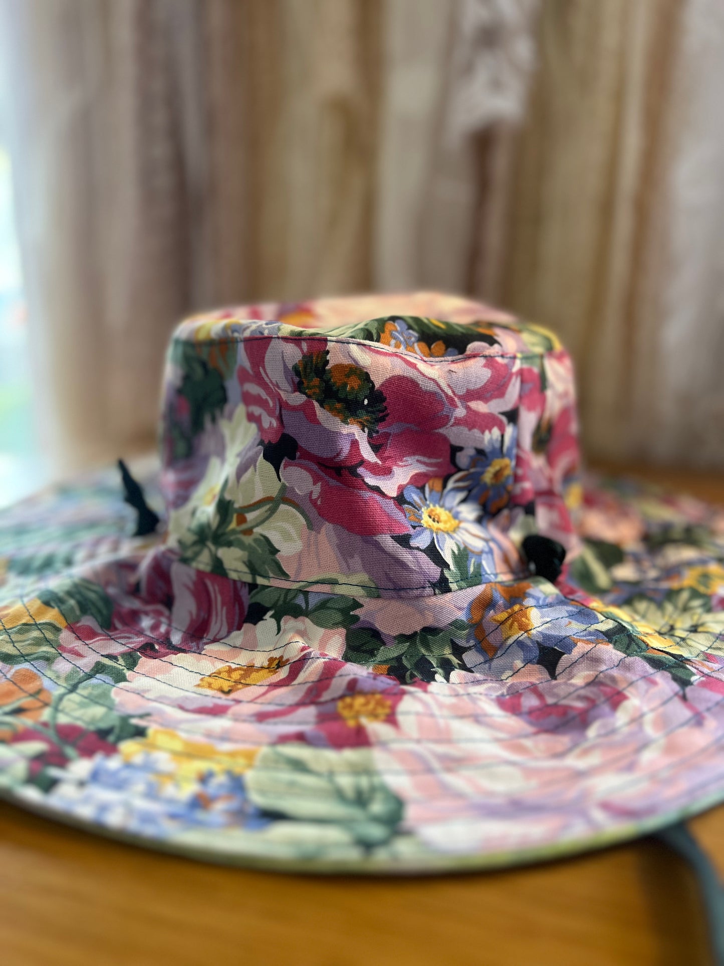 Floral-patterned hat on a wooden surface with a blurred background