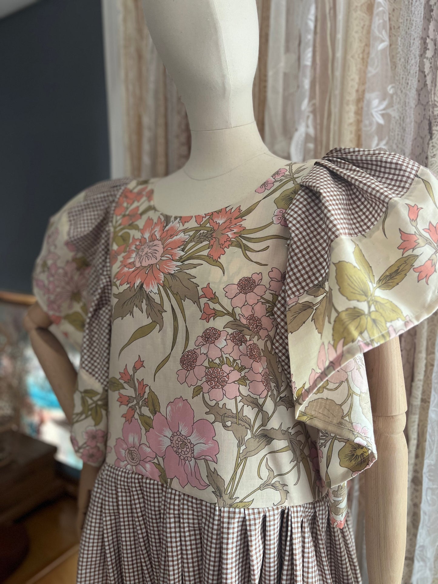 Mannequin wearing a floral dress with a checkered skirt in a store setting