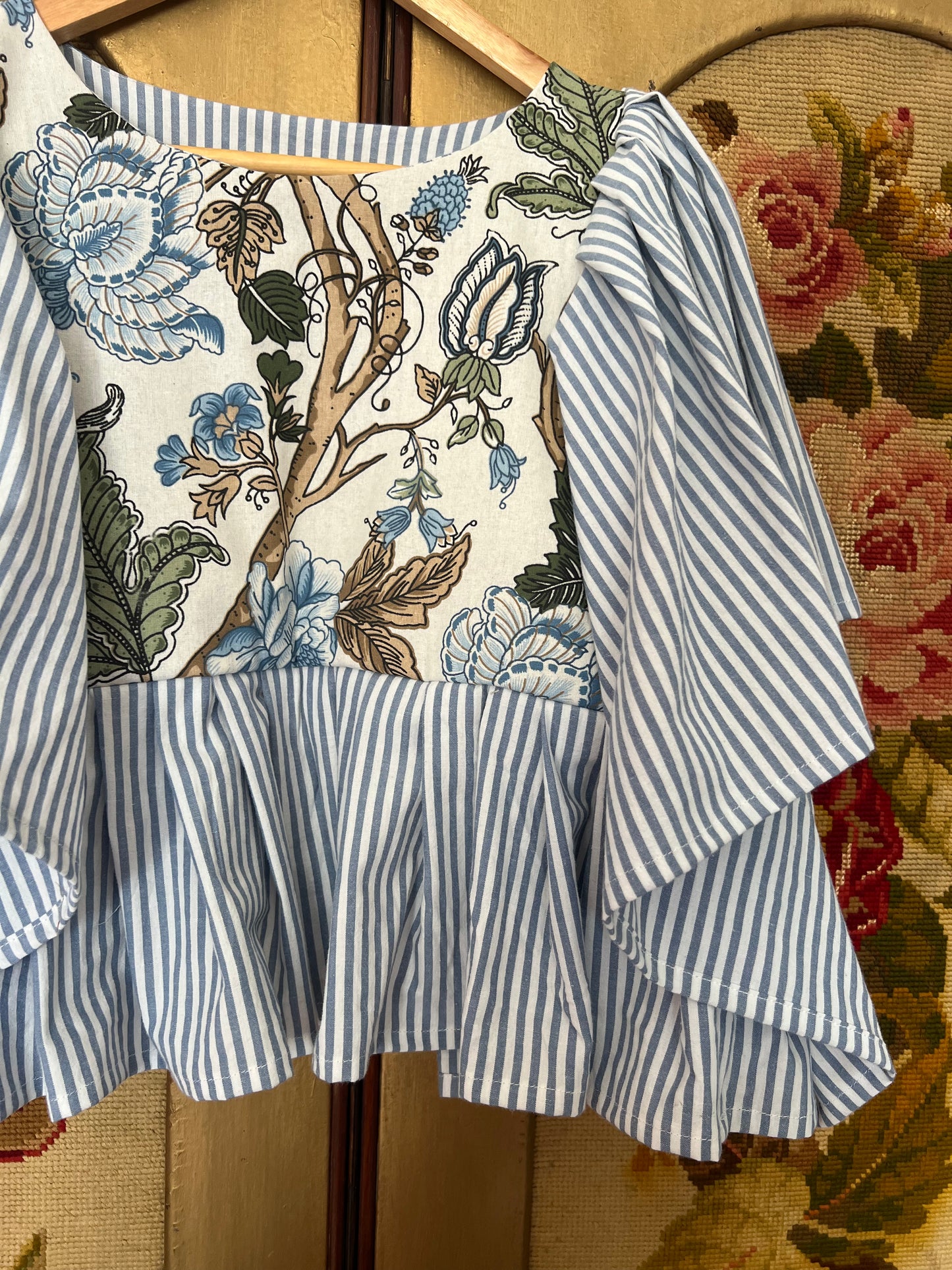 Blue and white striped dress with floral pattern on a mannequin against a floral background