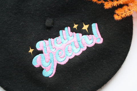 Black felt wool beret with an embroidered 'Hell Yeah' slogan in pink and blue to the top