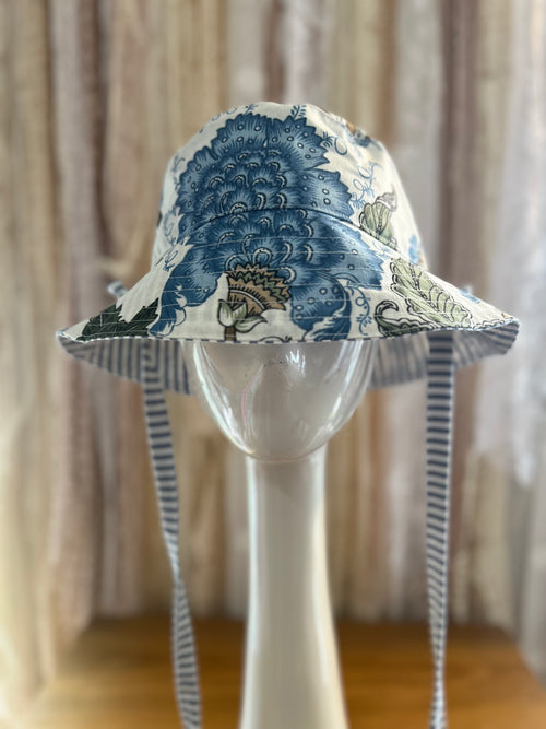 Blue and white patterned sun hat on a mannequin head with a neutral background