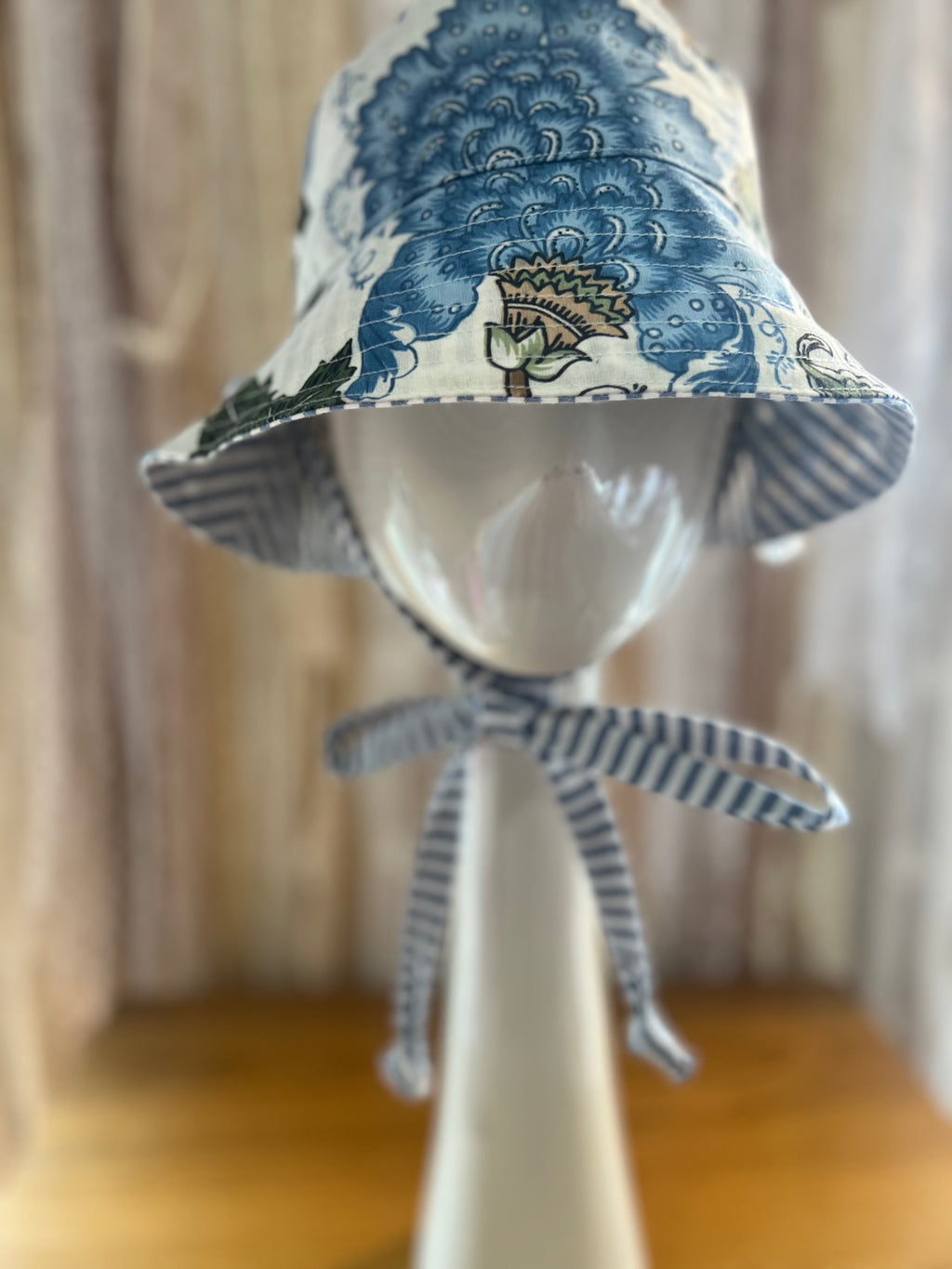 Blue and white patterned bucket haton a mannequin head with a blurred background