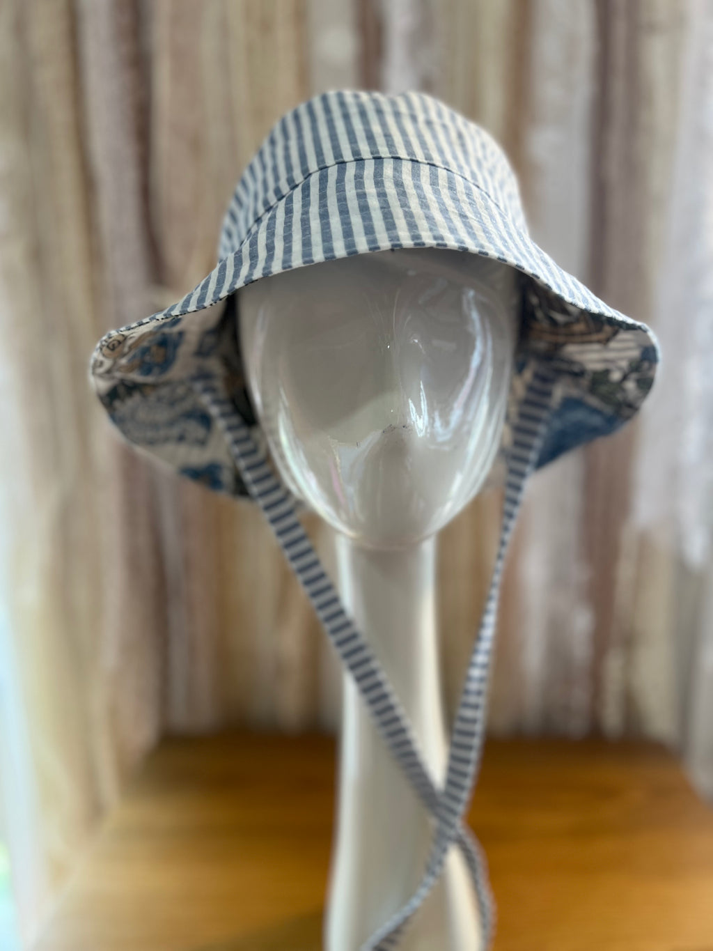 Blue and white striped sun hat on a mannequin head against a neutral background