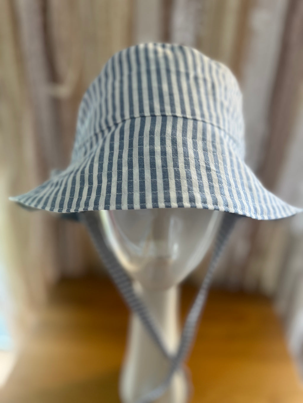 Blue and white striped bucket hat on a mannequin against a neutral background