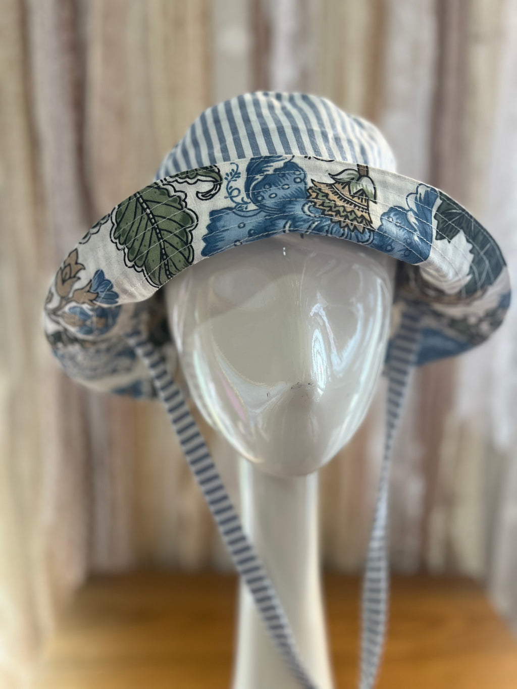Blue and white patterned sun hat on a mannequin head against a neutral background