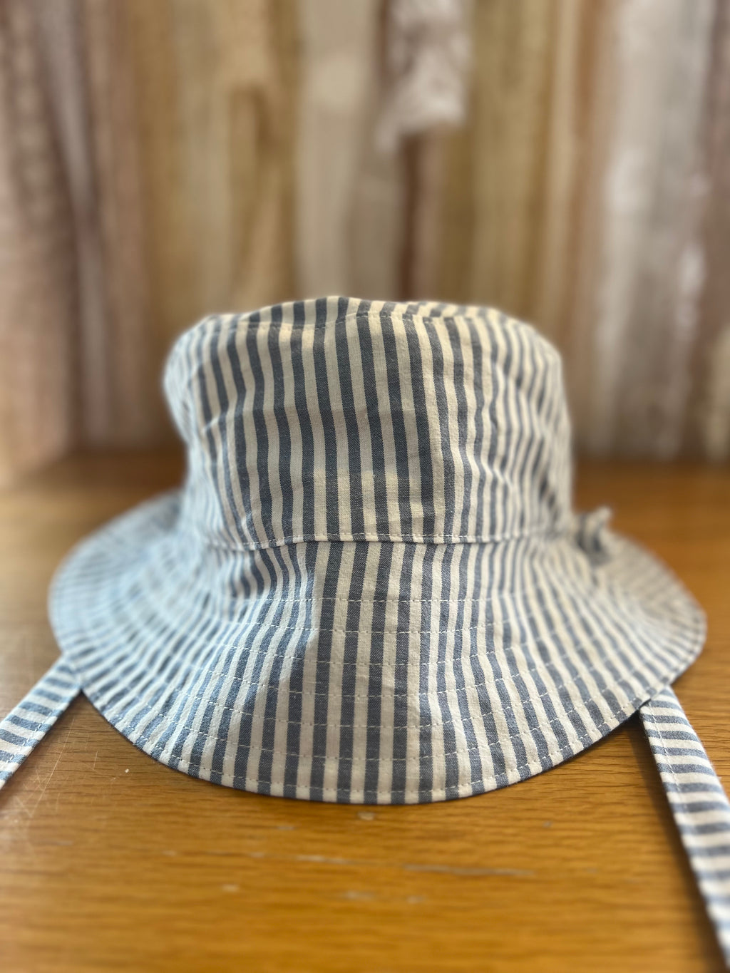 Striped bucket hat on a wooden surface with a neutral background