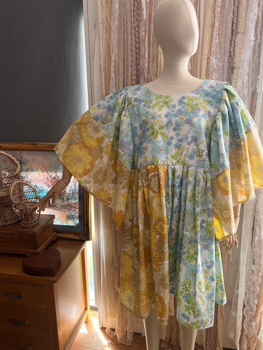 Mannequin wearing a floral dress in a room with curtains and a dresser.