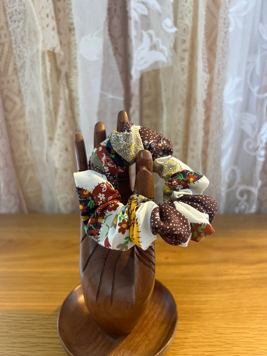 Decorative scrunchie with fabric flowers on a wooden stand against a lace curtain background