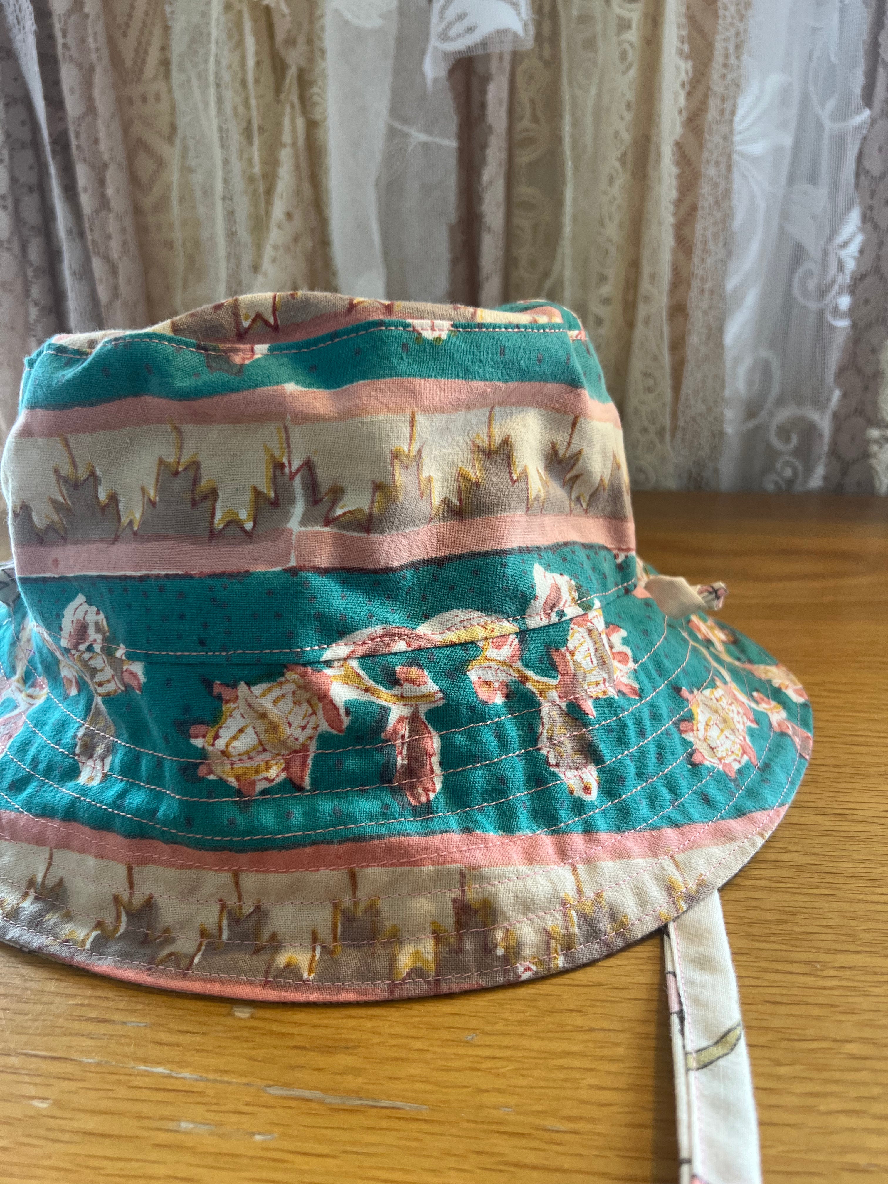 Floral-patterned bucket hat on a wooden surface with a curtain background