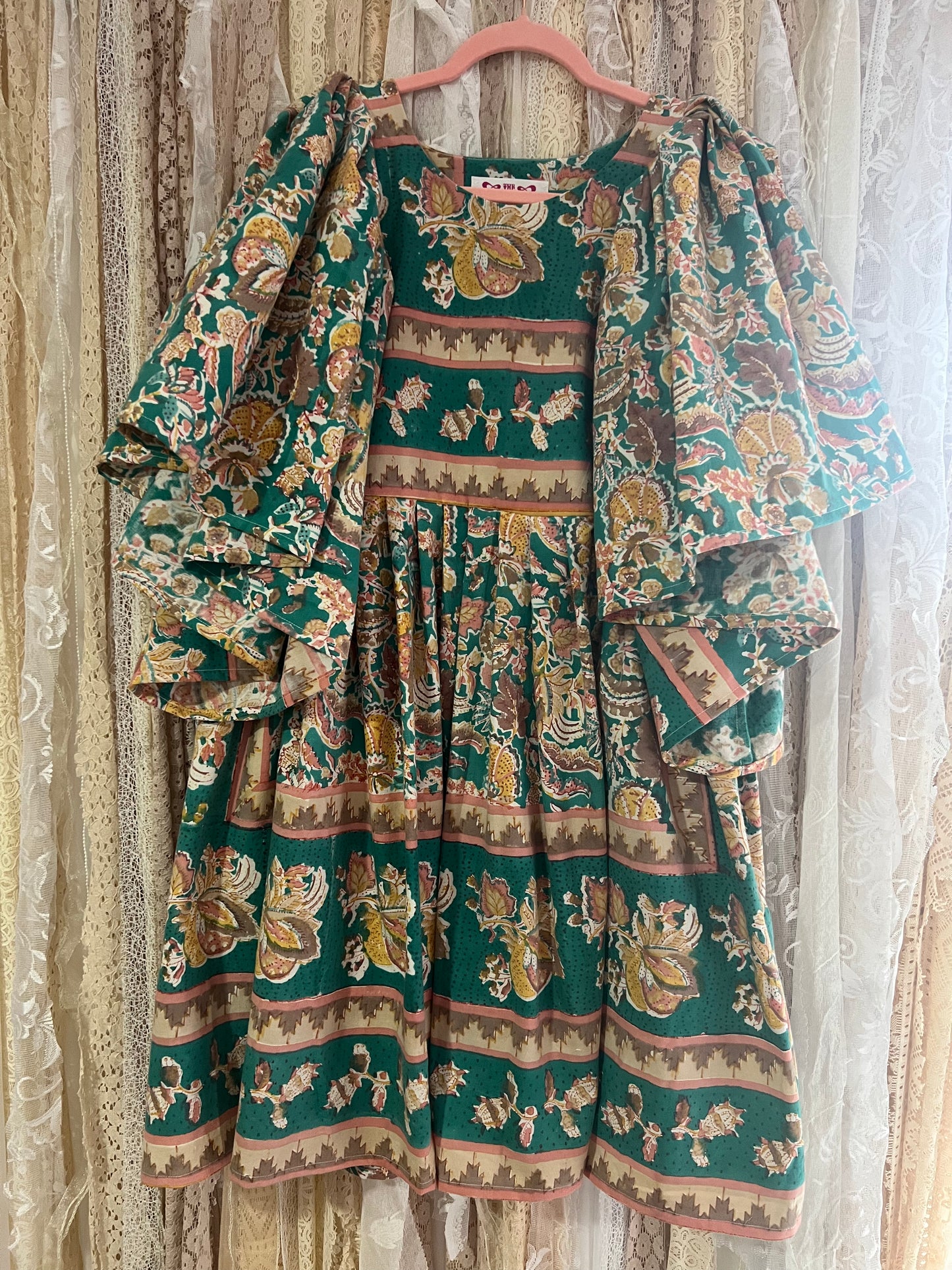 Traditional patterned dress on a hanger against a neutral background