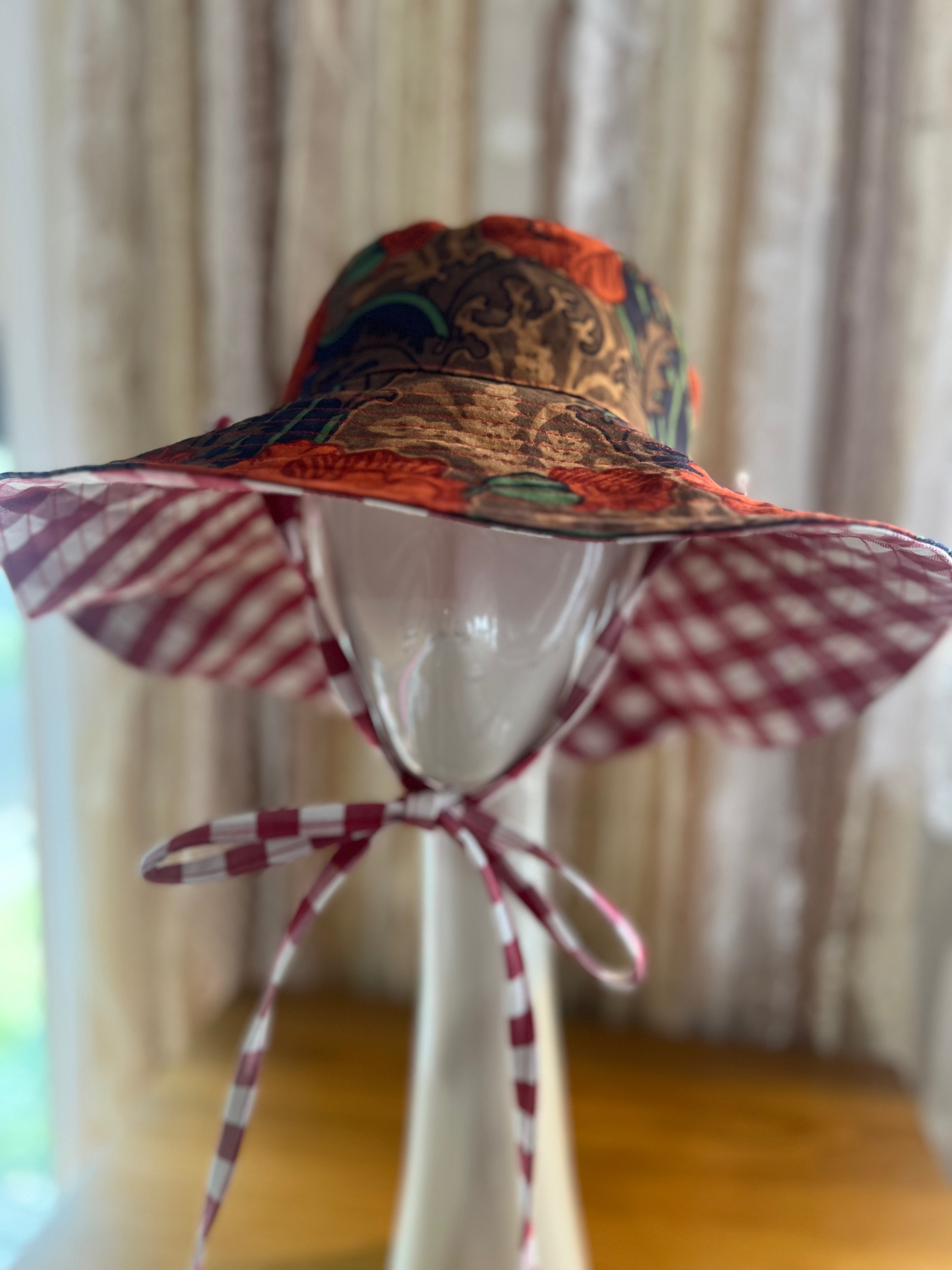 Colorful sun hat on a mannequin head with a checkered ribbon against a neutral background
