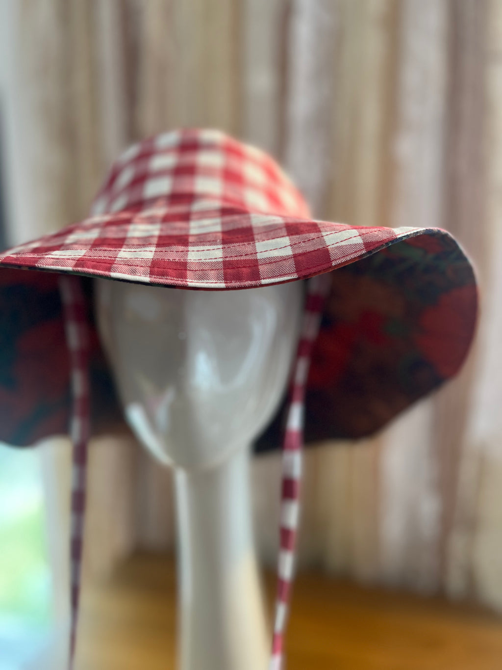 Red and white checkered hat on a mannequin against a neutral background