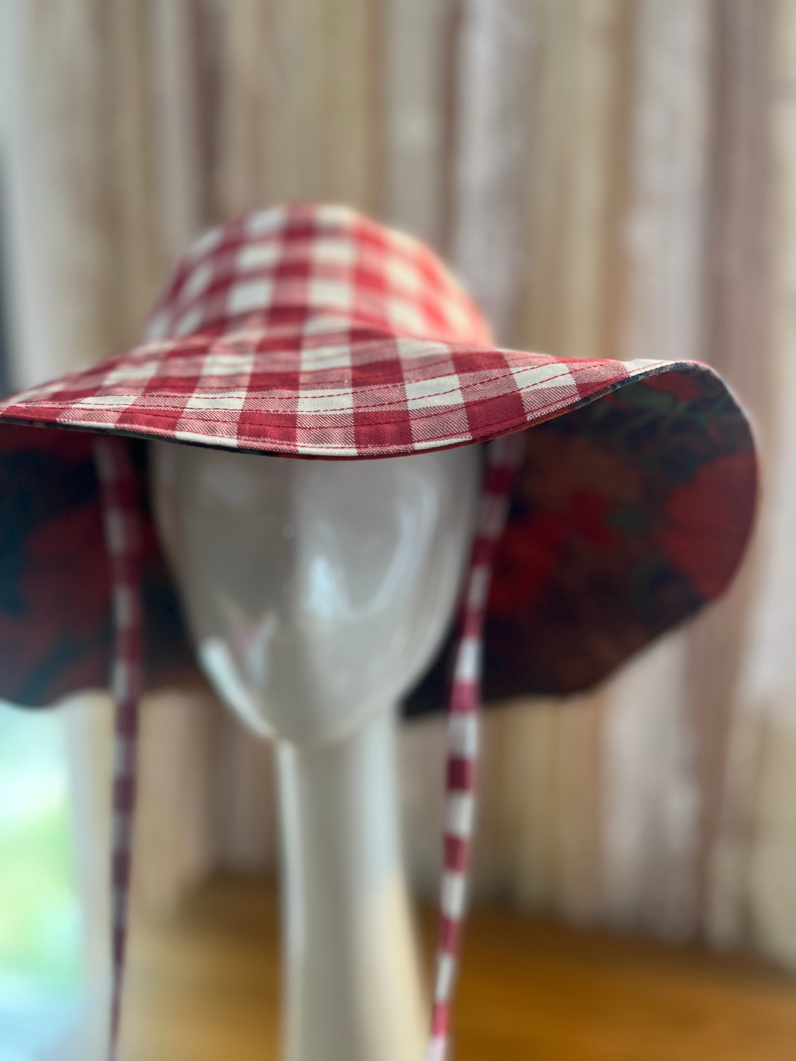 Red and white checkered hat on a mannequin against a neutral background