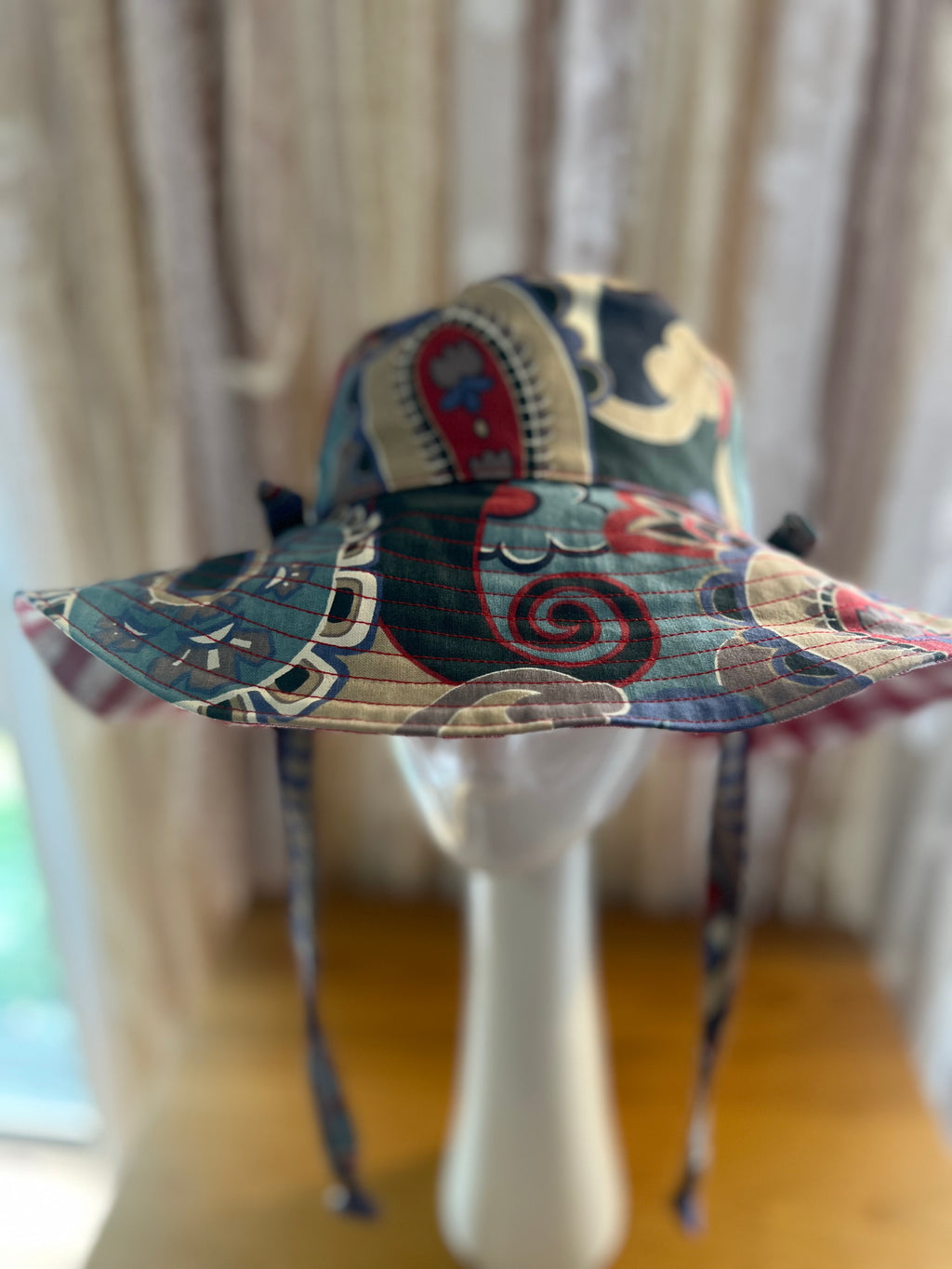 Colorful bucket hat with intricate patterns on a mannequin against a neutral background