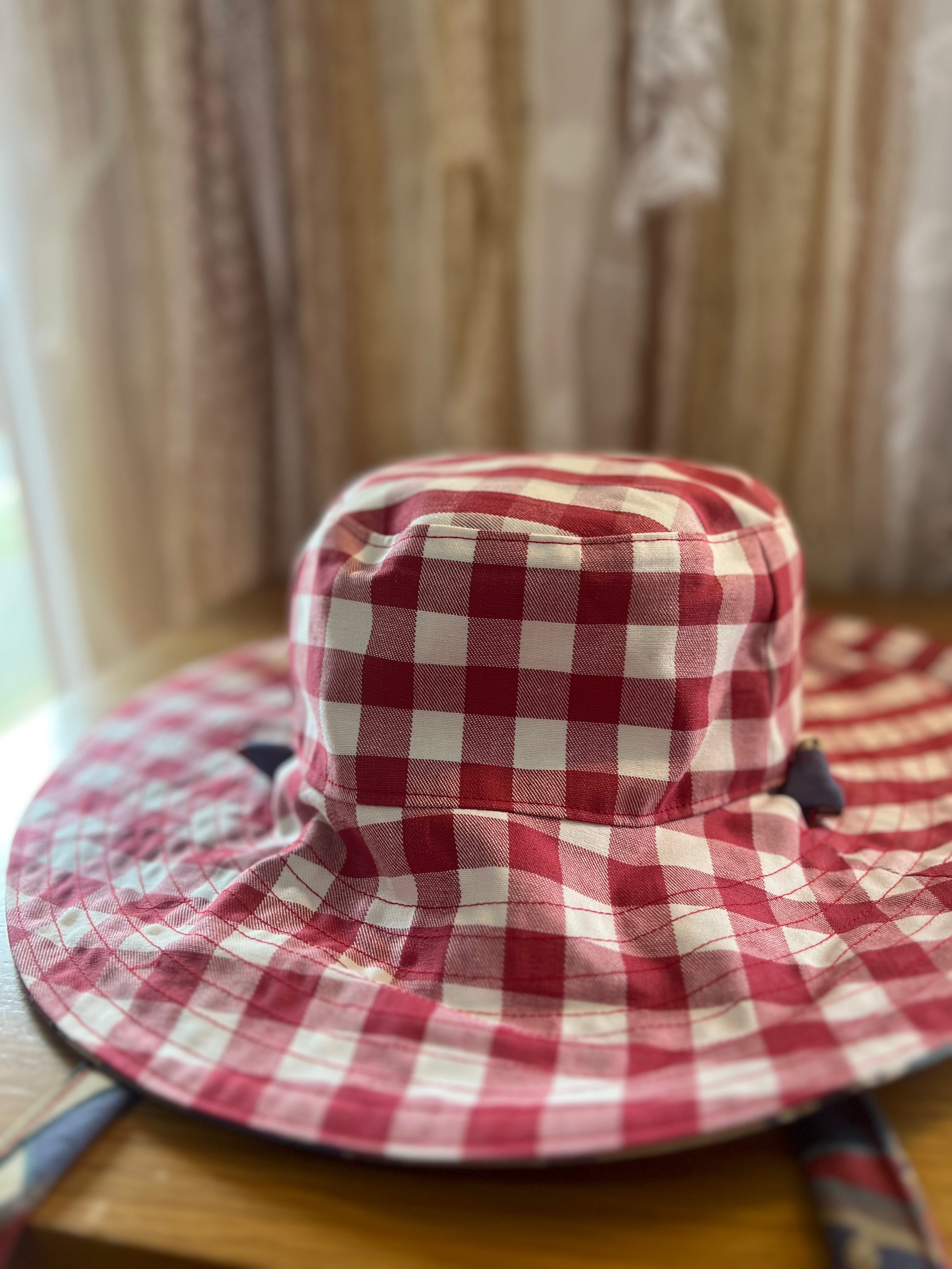 Red and white checkered bucket hat on a wooden surface with a blurred curtain background