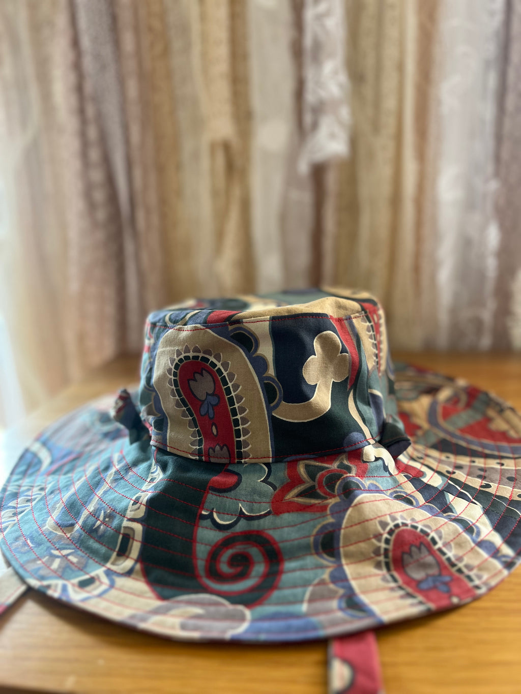 Colorful bucket hat with paisley pattern on a wooden surface