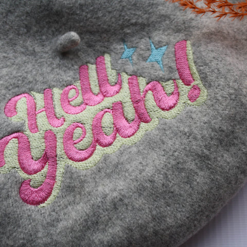 Grey felt wool beret with an embroidered 'Hell Yeah' slogan in pink and yellow to the top