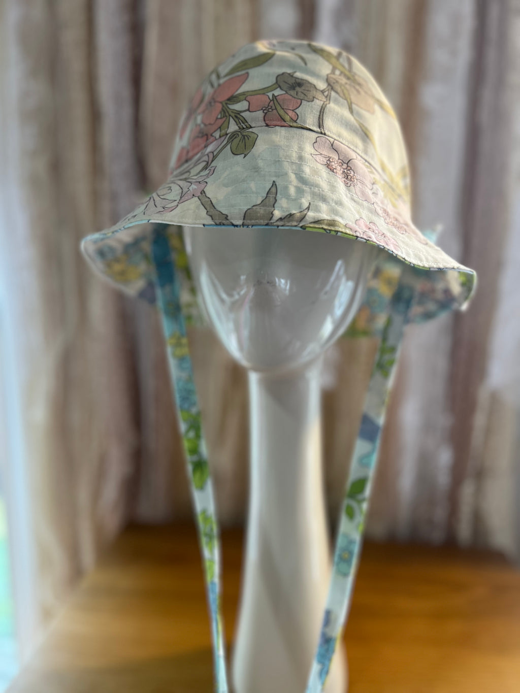 Floral-patterned bucket hat on a mannequin head against a neutral background