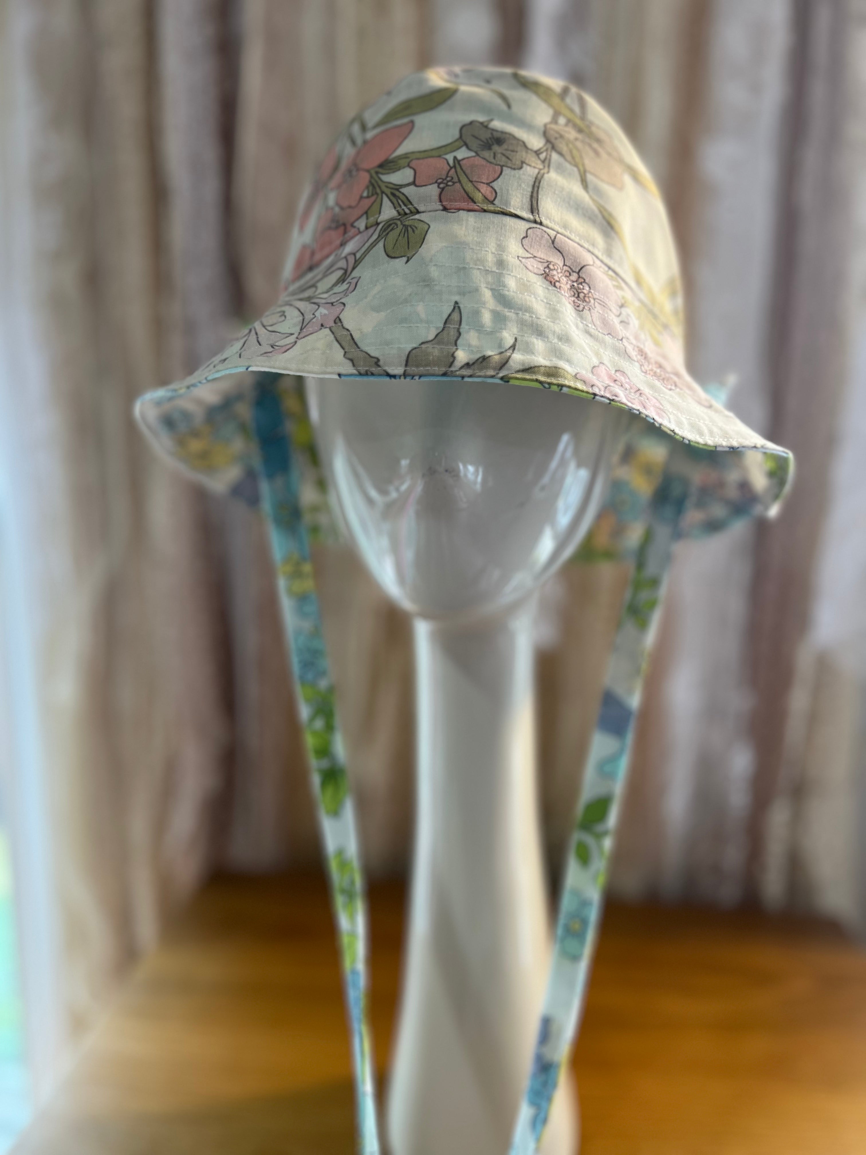 Floral-patterned bucket hat on a mannequin head against a neutral background