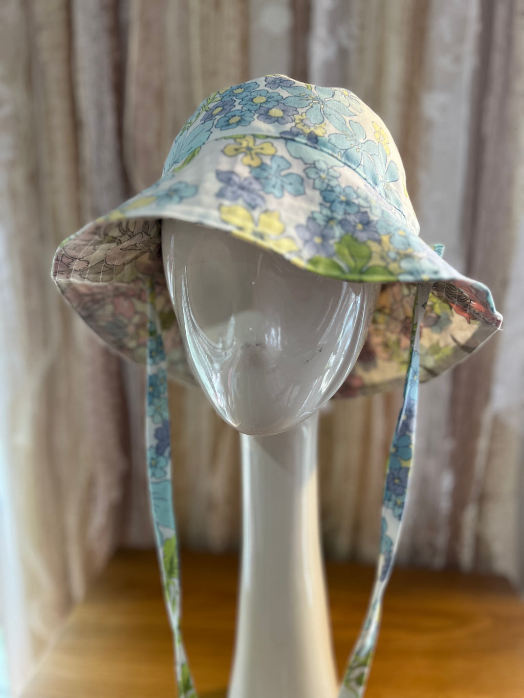 Floral-patterned sun hat on a mannequin head against a neutral background