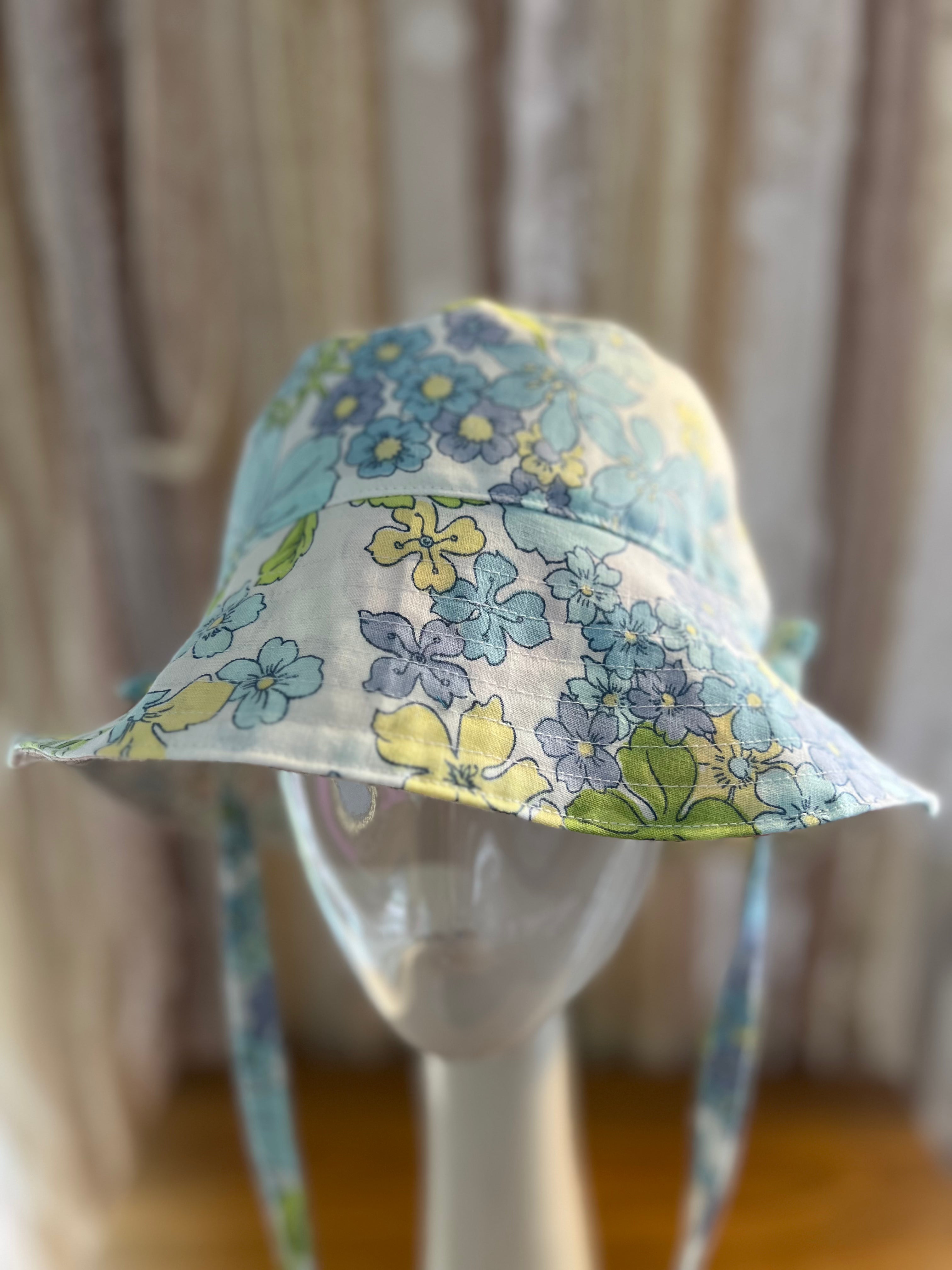 Floral-patterned sun hat on a mannequin against a neutral background