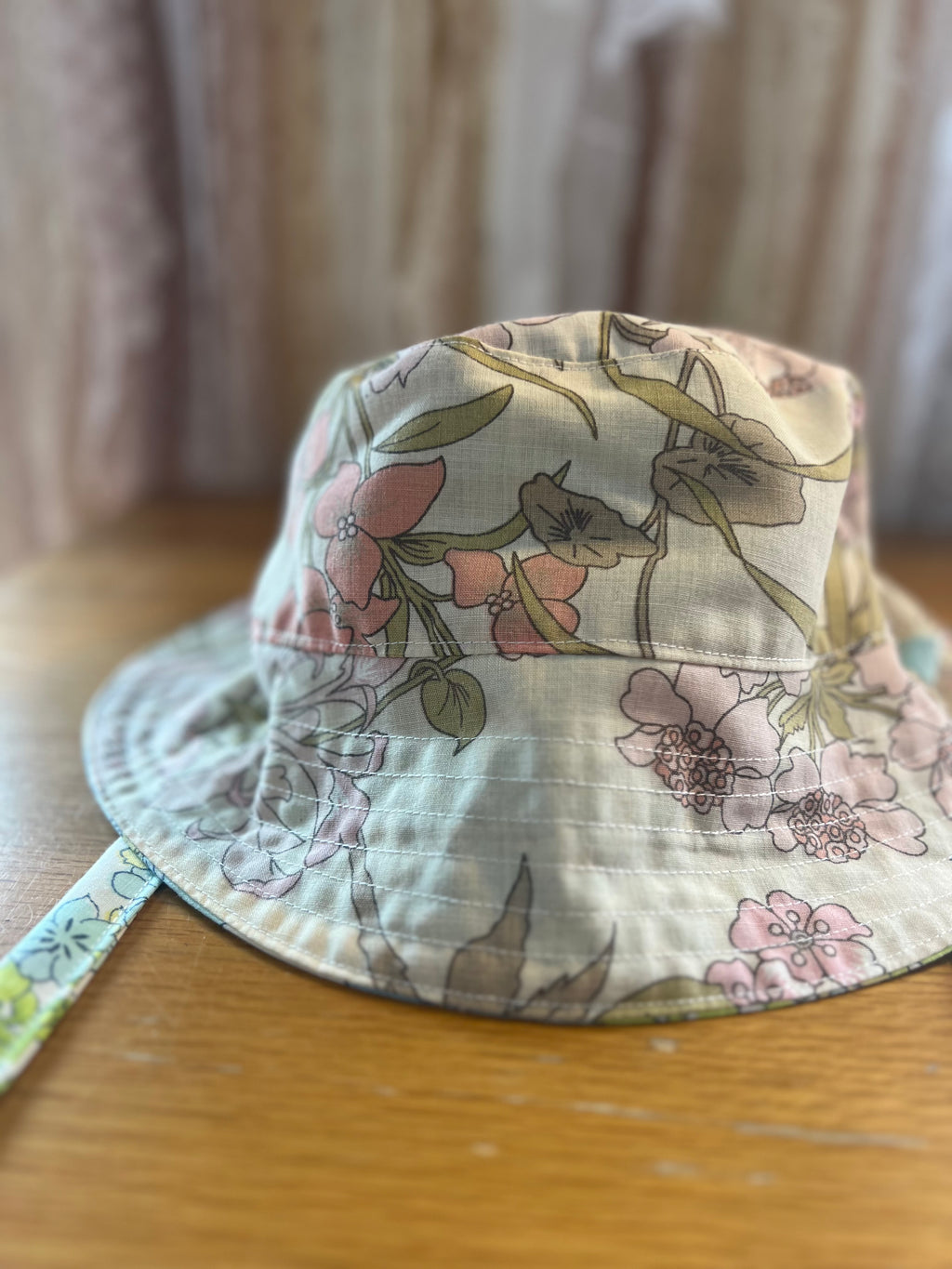 Floral-patterned bucket hat on a wooden surface with a blurred background