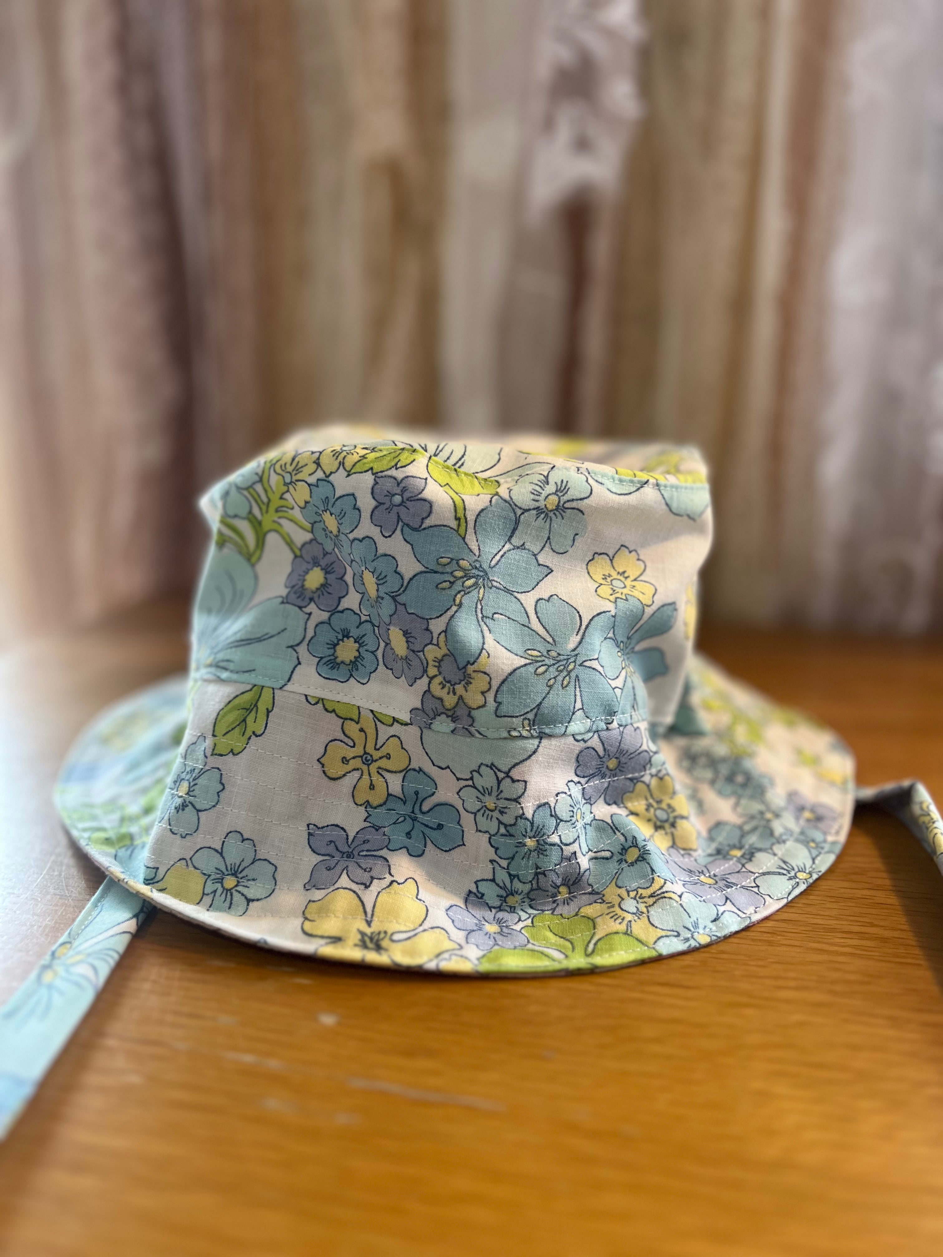 Floral-patterned bucket hat on a wooden surface with a neutral background