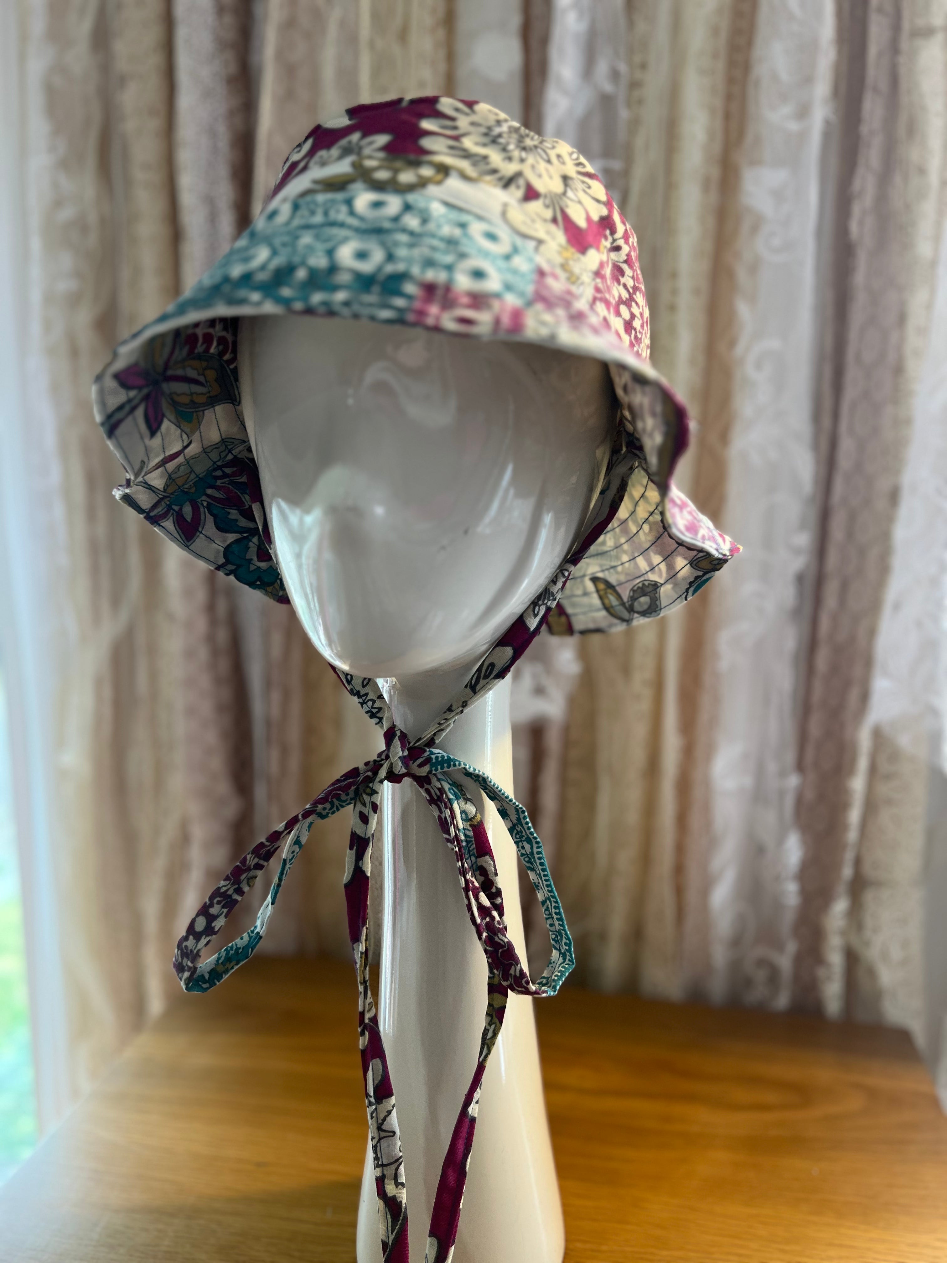 Floral patterned sun hat on a mannequin head against a neutral background