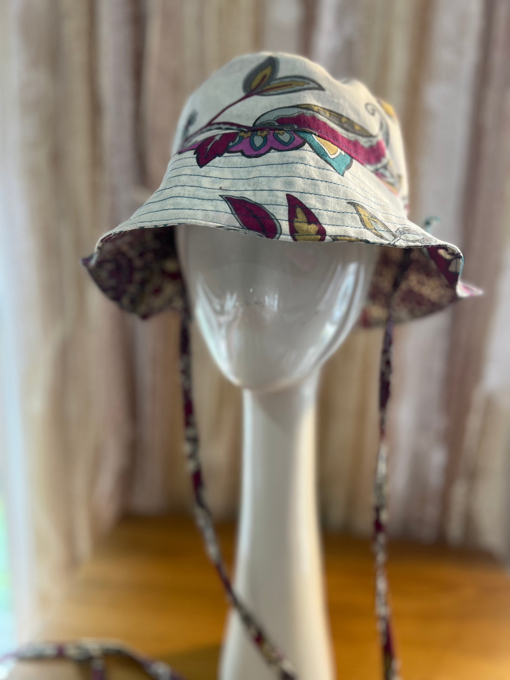 Floral-patterned bucket hat on a mannequin head with a neutral background
