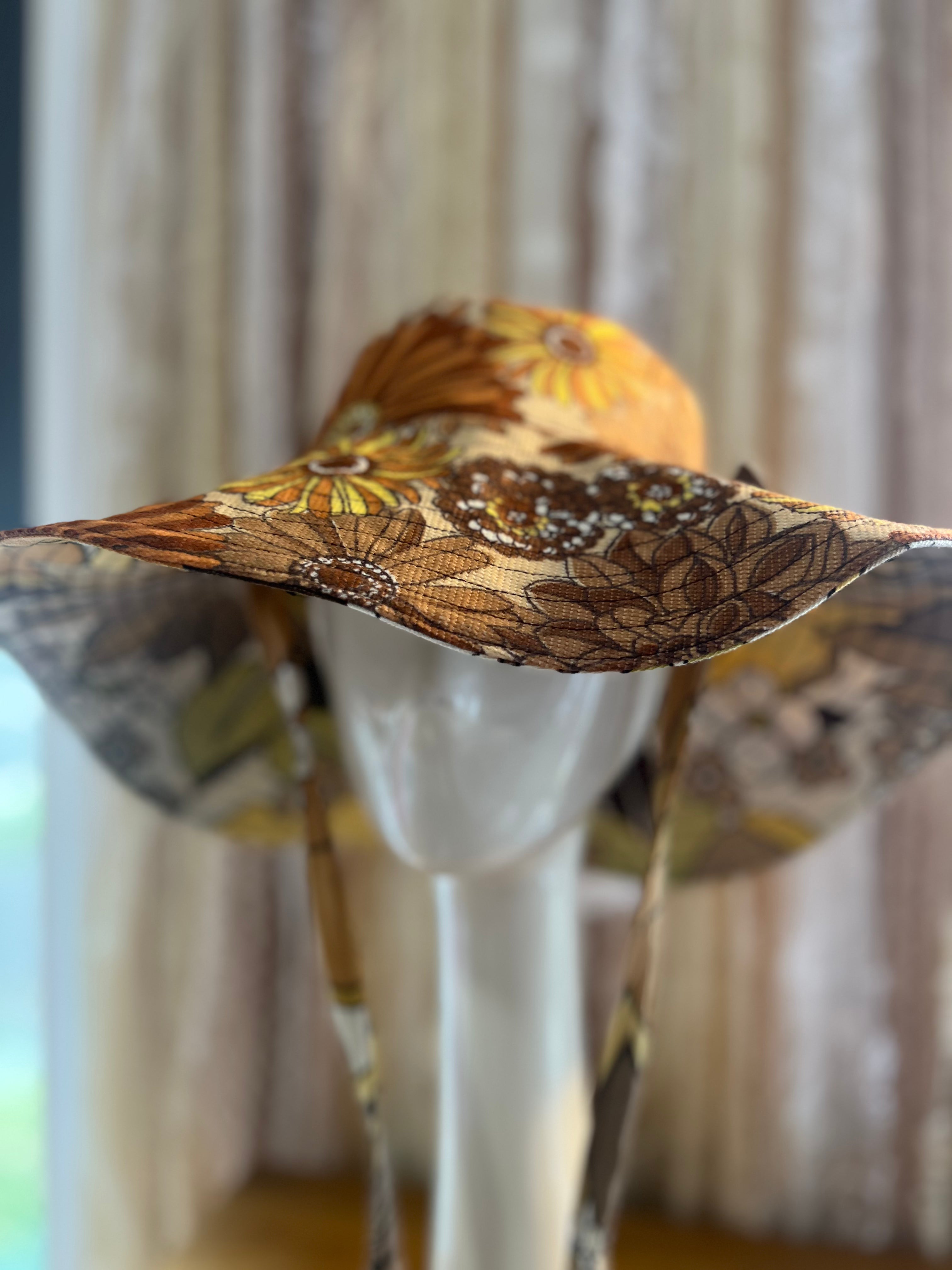 Decorative hat with intricate patterns on a mannequin against a neutral background