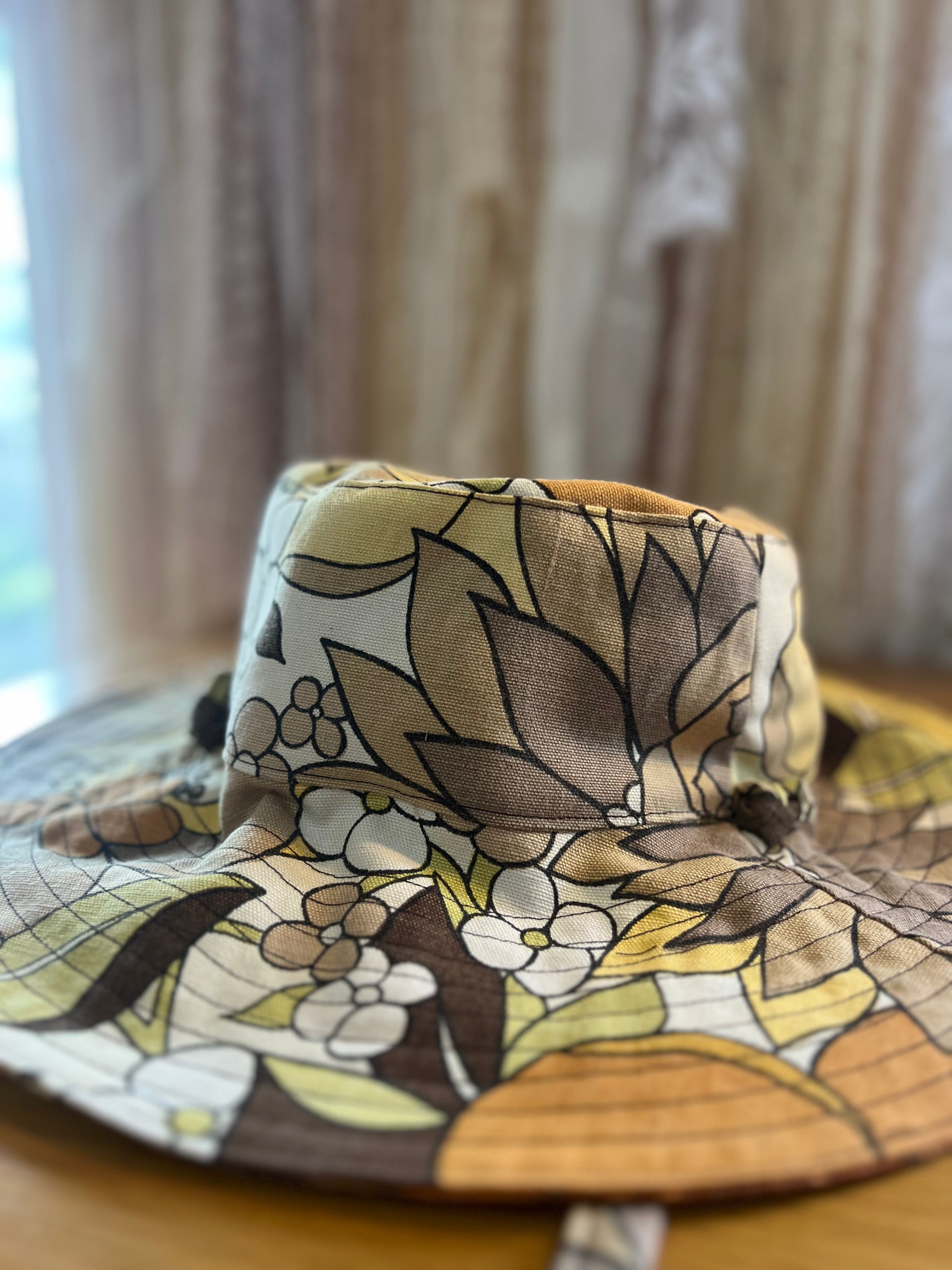 Floral-patterned fabric hat on a wooden surface with a blurred background