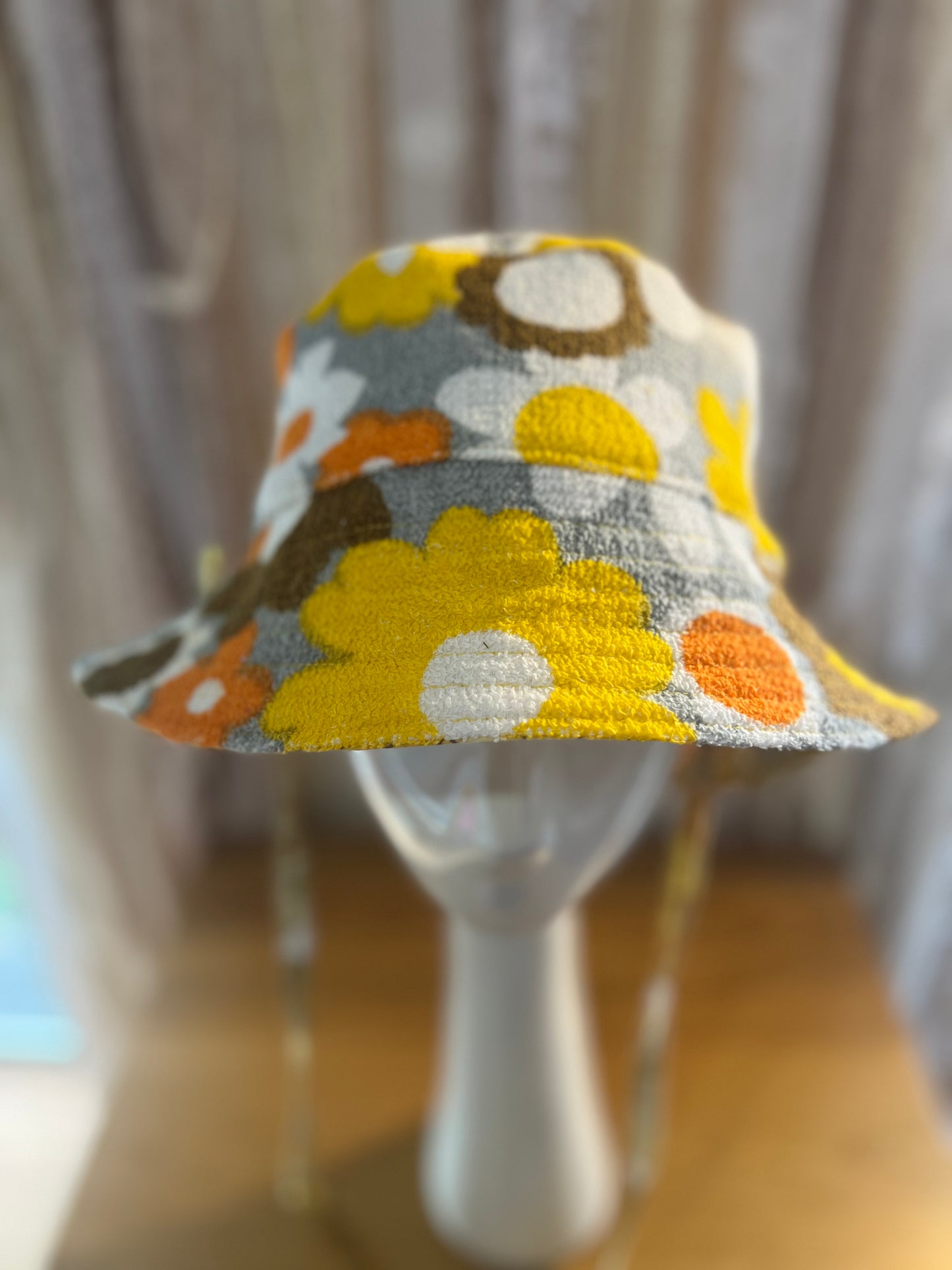 Colorful floral-patterned hat on a mannequin against a neutral background