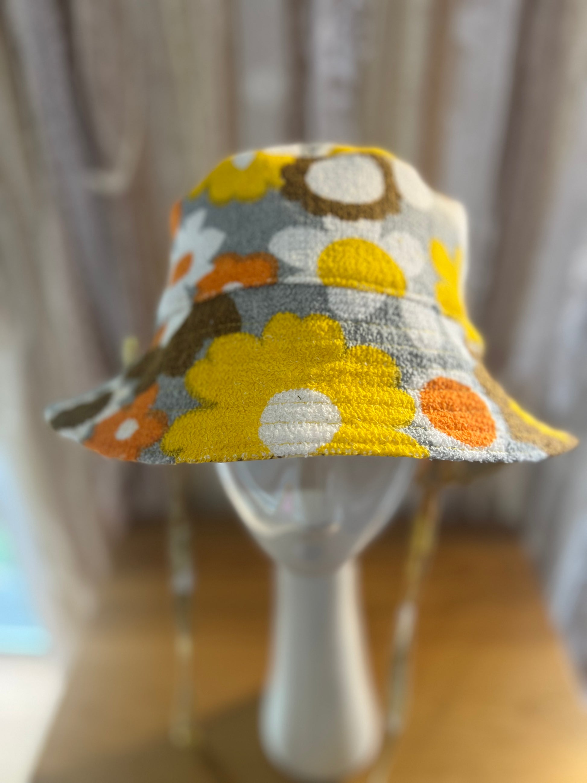 Colorful floral-patterned hat on a mannequin against a neutral background