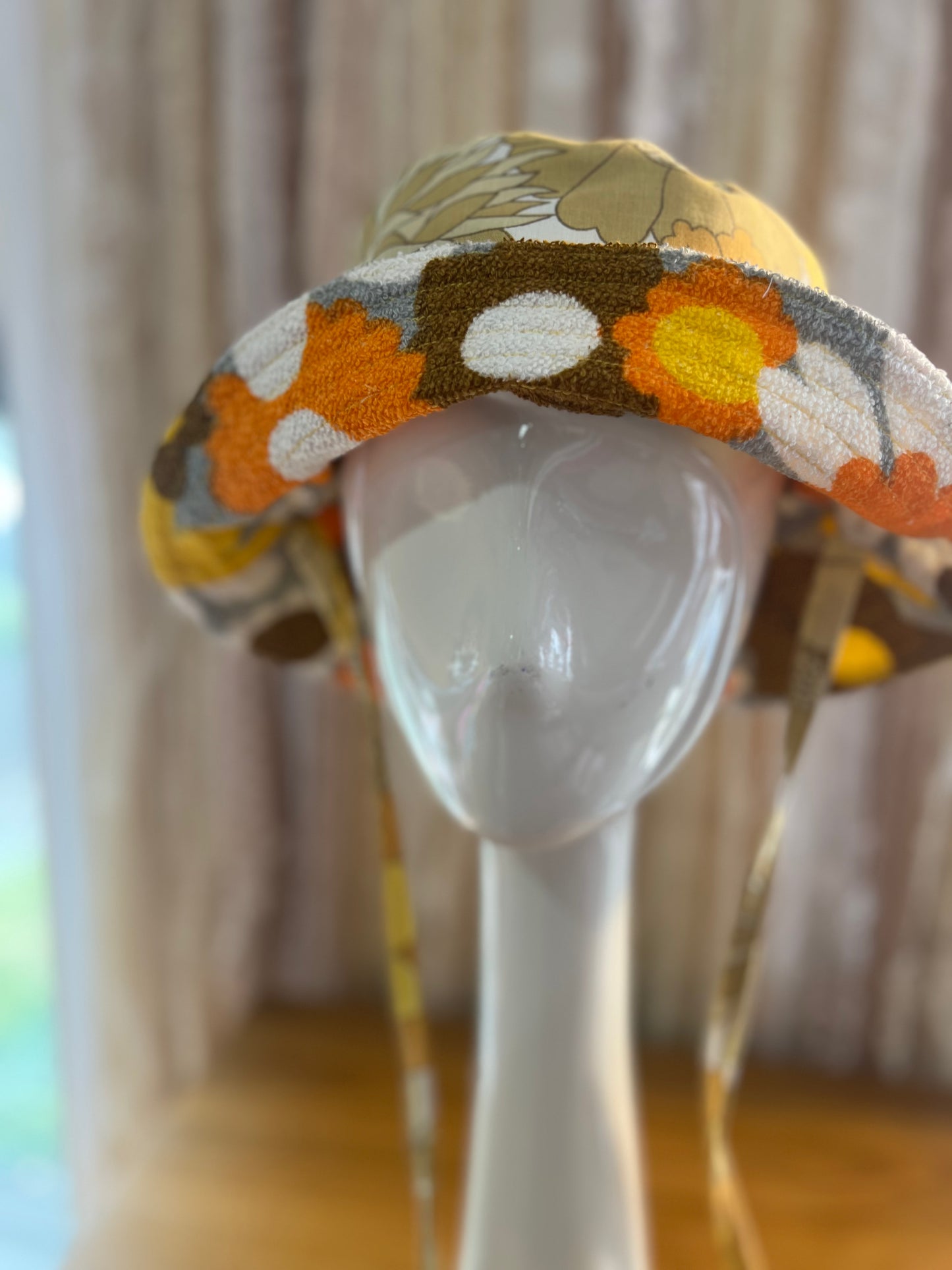 Decorative hat with floral pattern on a mannequin head against a neutral background