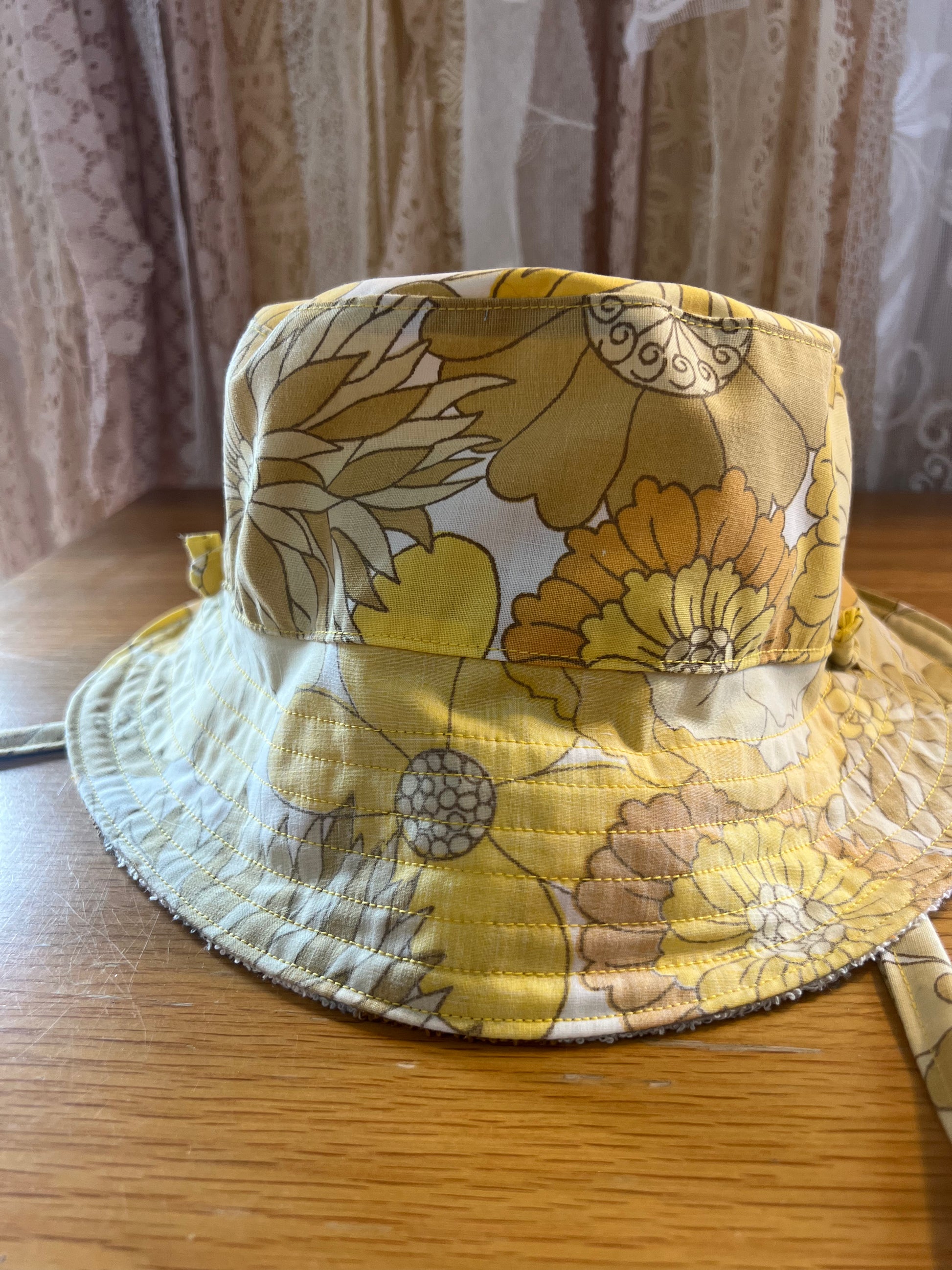 Floral-patterned bucket hat on a wooden surface with a curtain background