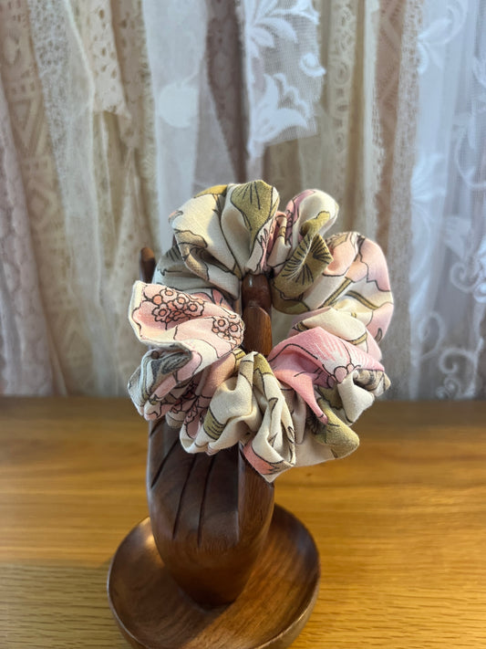Decorative scrunchie with floral patterns in a wooden holder on a wooden surface.